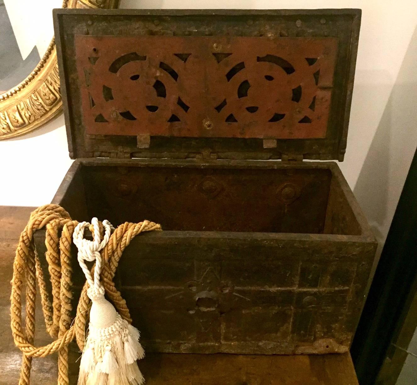 The flat topped chest with concealed keyhole, bound in iron, with iron strapwork punctuated by studs to the exterior, opening to an ornate spring loaded locking system behind a pierced grill to the underside of the lid, loop handles to either end