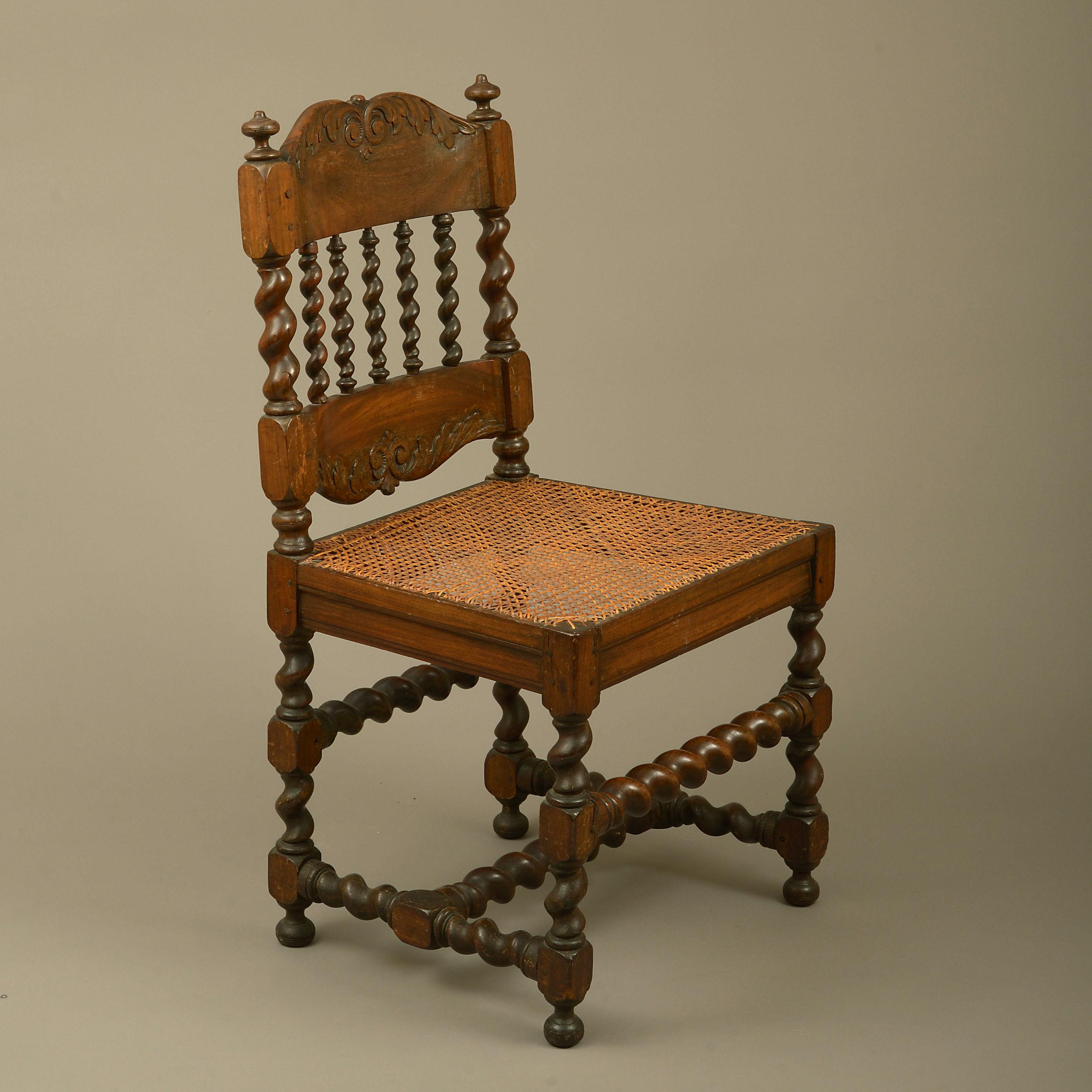 A rare pair of early 18th century Cape Dutch stinkwood side chairs, each having a shaped and carved top rail upon barley twist spindle supports, the caned seats terminating in barley twist legs and stretchers.
 