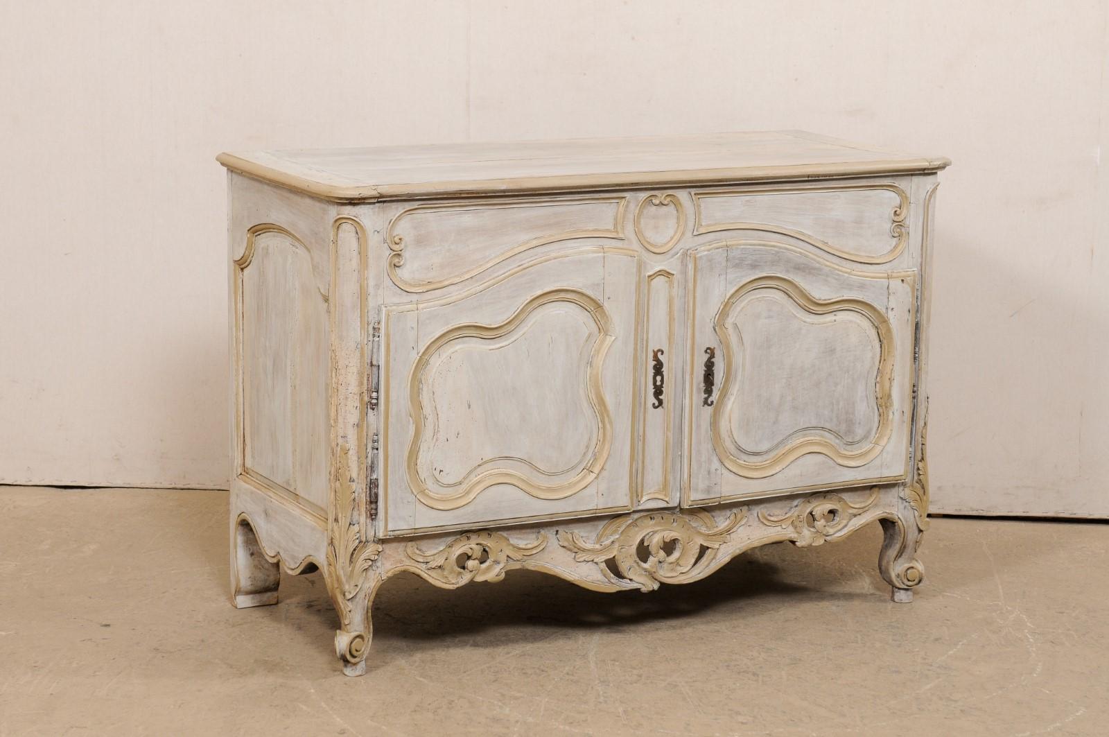 A French two-door buffet cabinet with nicely carved skirt from the early 19th century (or possibly earlier). This antique painted and carved wood cabinet from France has a rectangular-shaped top with rounded front corner edges, which rests above a