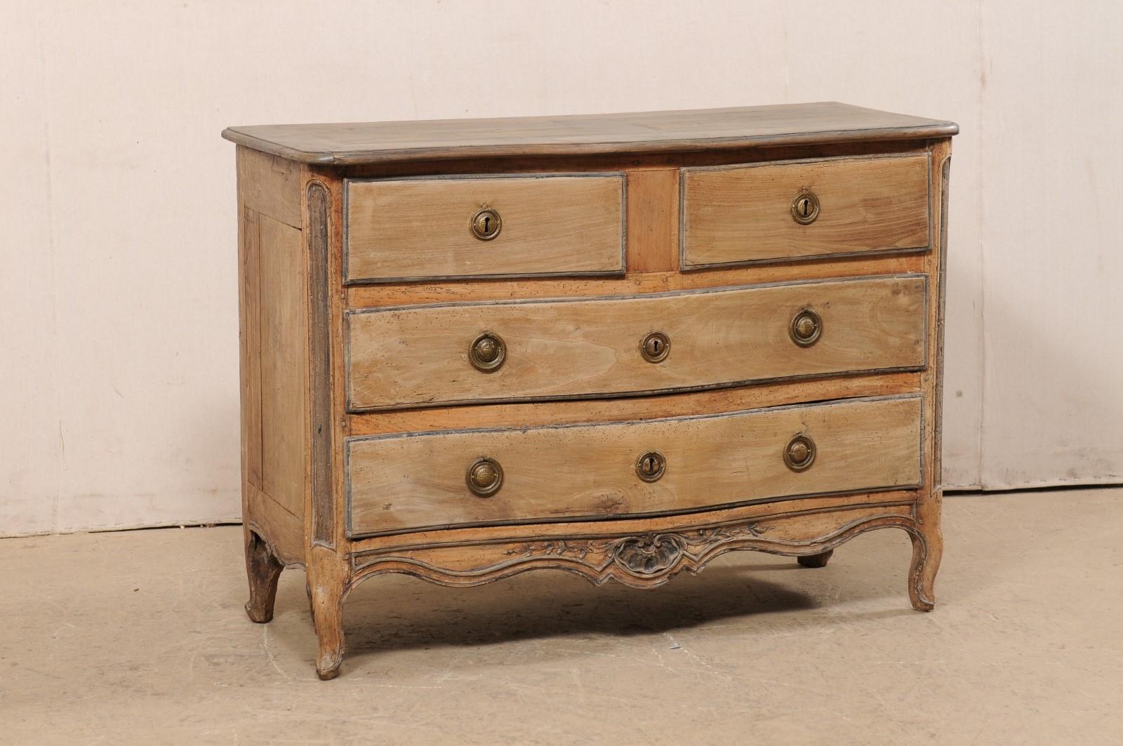 A French carved-wood serpentine commode, with slender depth, from the early 19th century. This antique chest from France has been designed with a subtle serpentine-shaped body, with skirt carved on three sides, and raised on four petitely-carved
