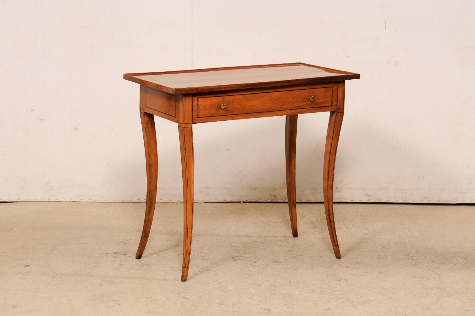 An elegant Italian carved-wood occasional table with single drawer, from the early 19th century. This antique table from Italy features a rectangular-shaped top with raised lip that gives it a tray-style top (though not removable), with a