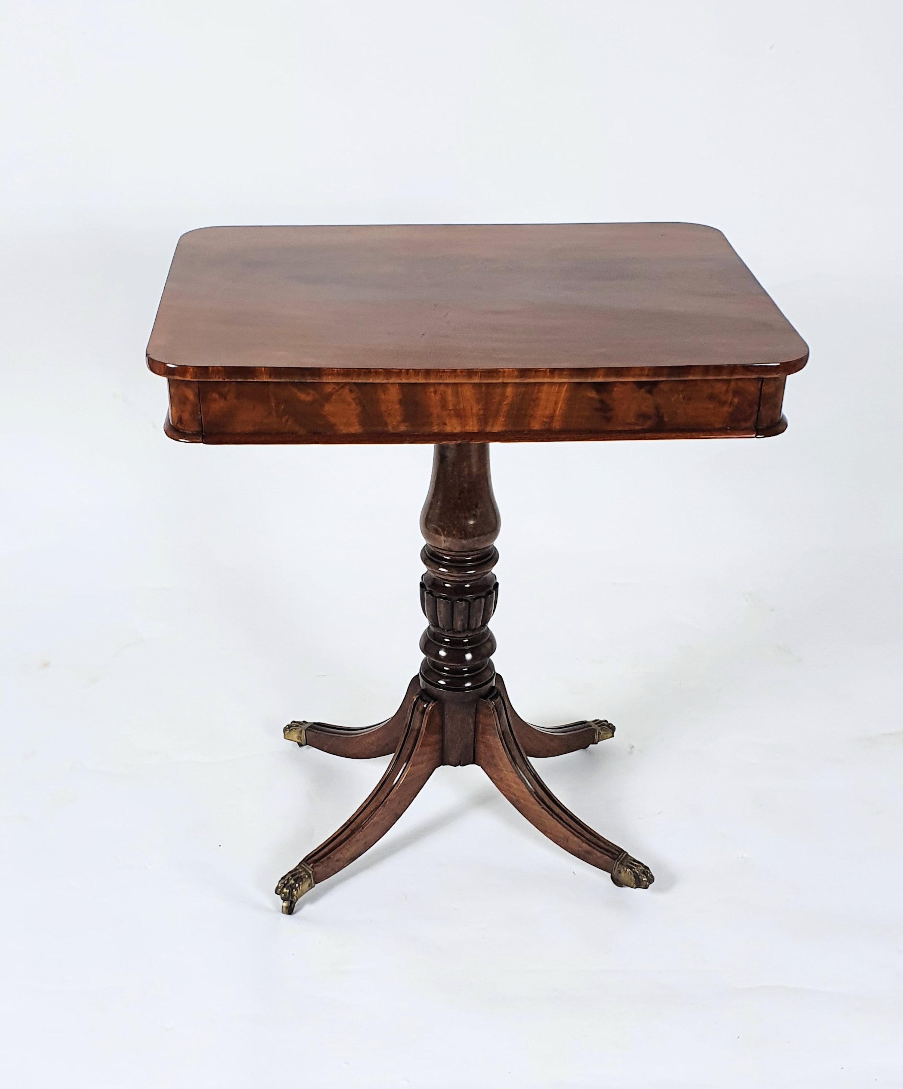 This early 19th century mahogany centre table features a frieze drawer and stands on a turned and fluted column with 4 reeded splay supports and original brass lions paw castors. It measures: 25 ½ in, 64.7 cm wide, 19 in, 48.3 cm deep and 28 ½, 72.4