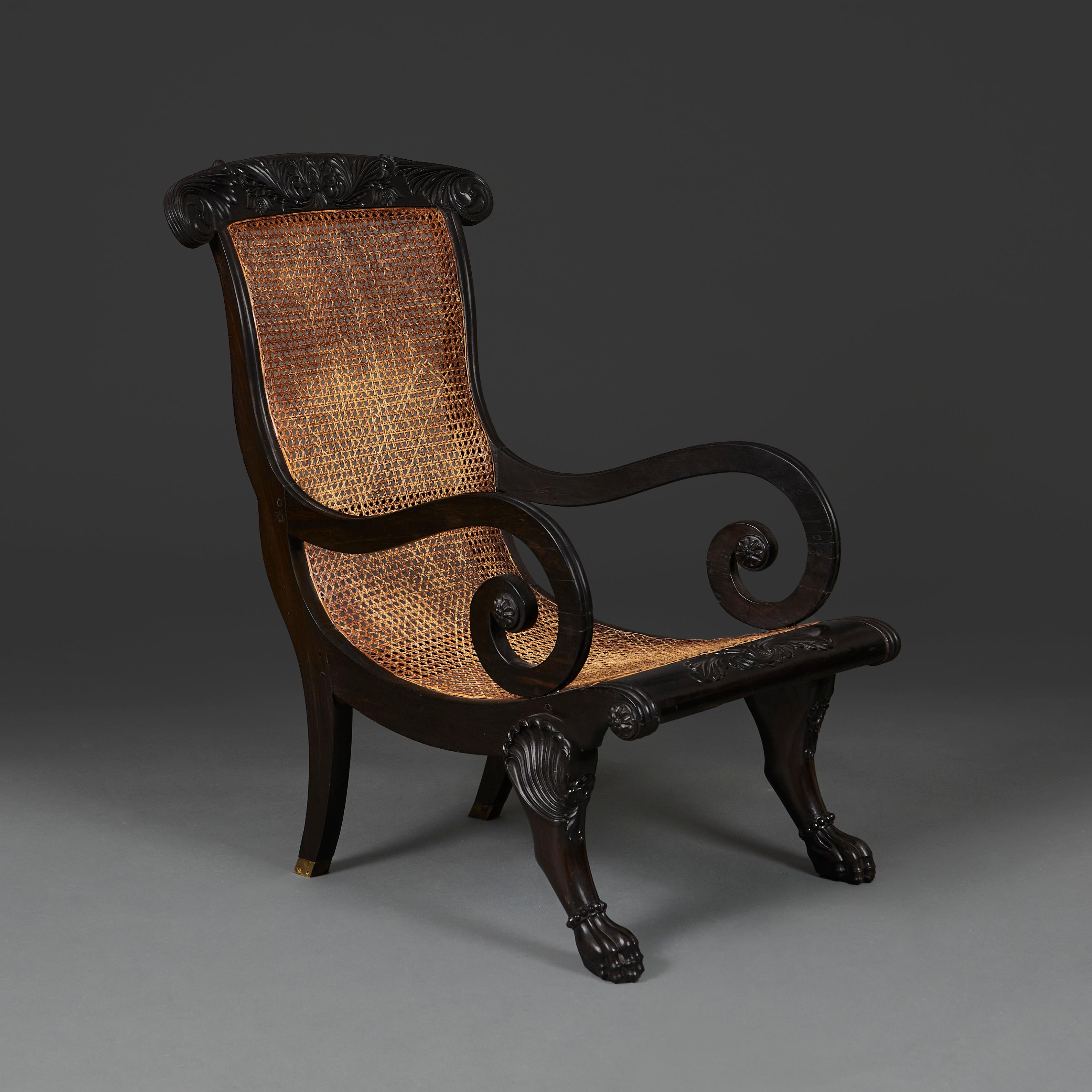 Sri-Lanka, circa 1820

An exceptional mid nineteenth century Anglo Sinhalese planters chair, of solid ebony construction, with scoop caned seat and scrolling arms, the seat rail and top of the back carved with foliate designs, the front two legs