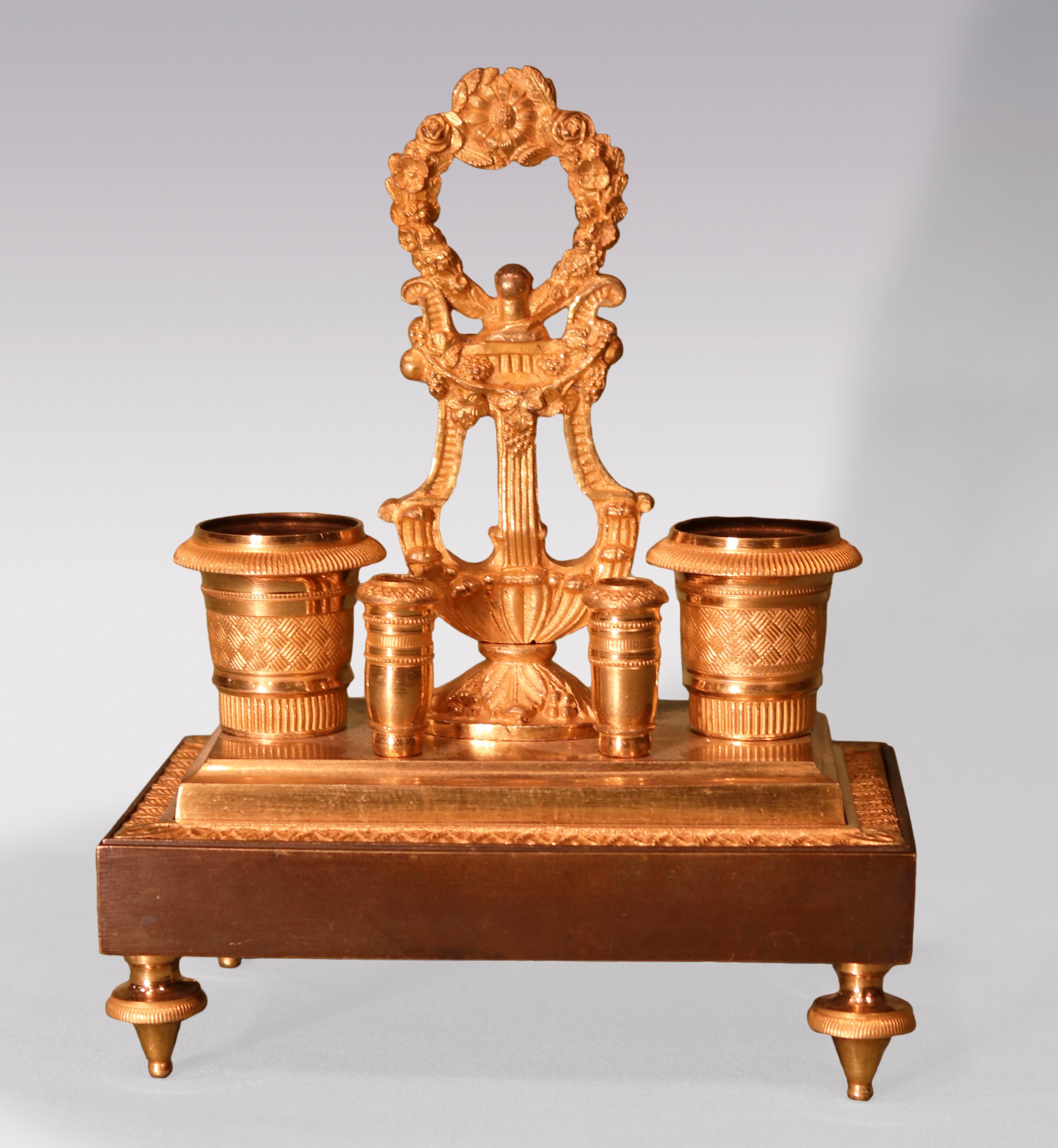 Ein Encrier aus Bronze und Ormolu aus dem frühen 19. Jahrhundert mit Lyra- und Blumengriff, flankiert von maschinell gedrechselten Tintenfässern mit Federhaltern, erhöht auf einem Sockel, der auf Toupetfüßen endet.