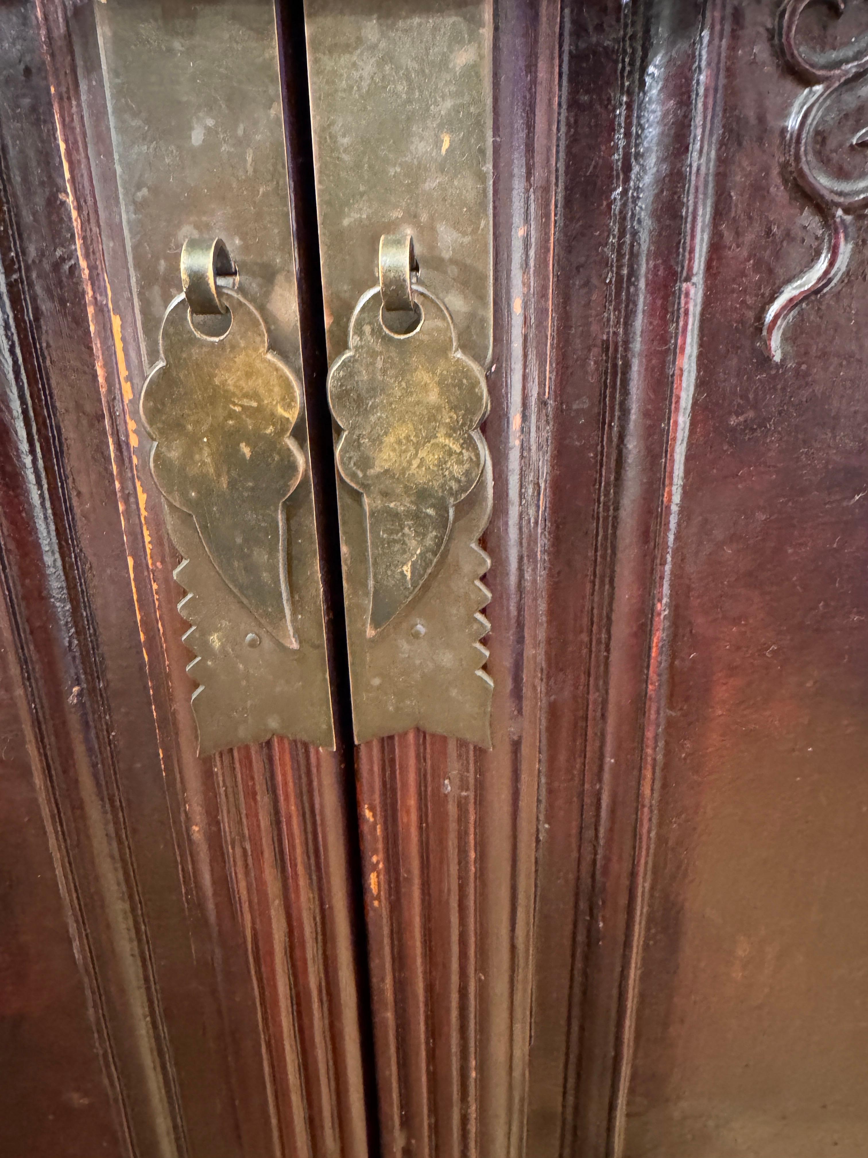 Mueble de madera de olmo de color marrón rojizo de la provincia china de Shanxi, ricamente entonada, con dos puertas de cuarterones con restos de mariposas y escrituras pintadas a mano, sobre dos cajones que forman parte de un subsuelo de celosía