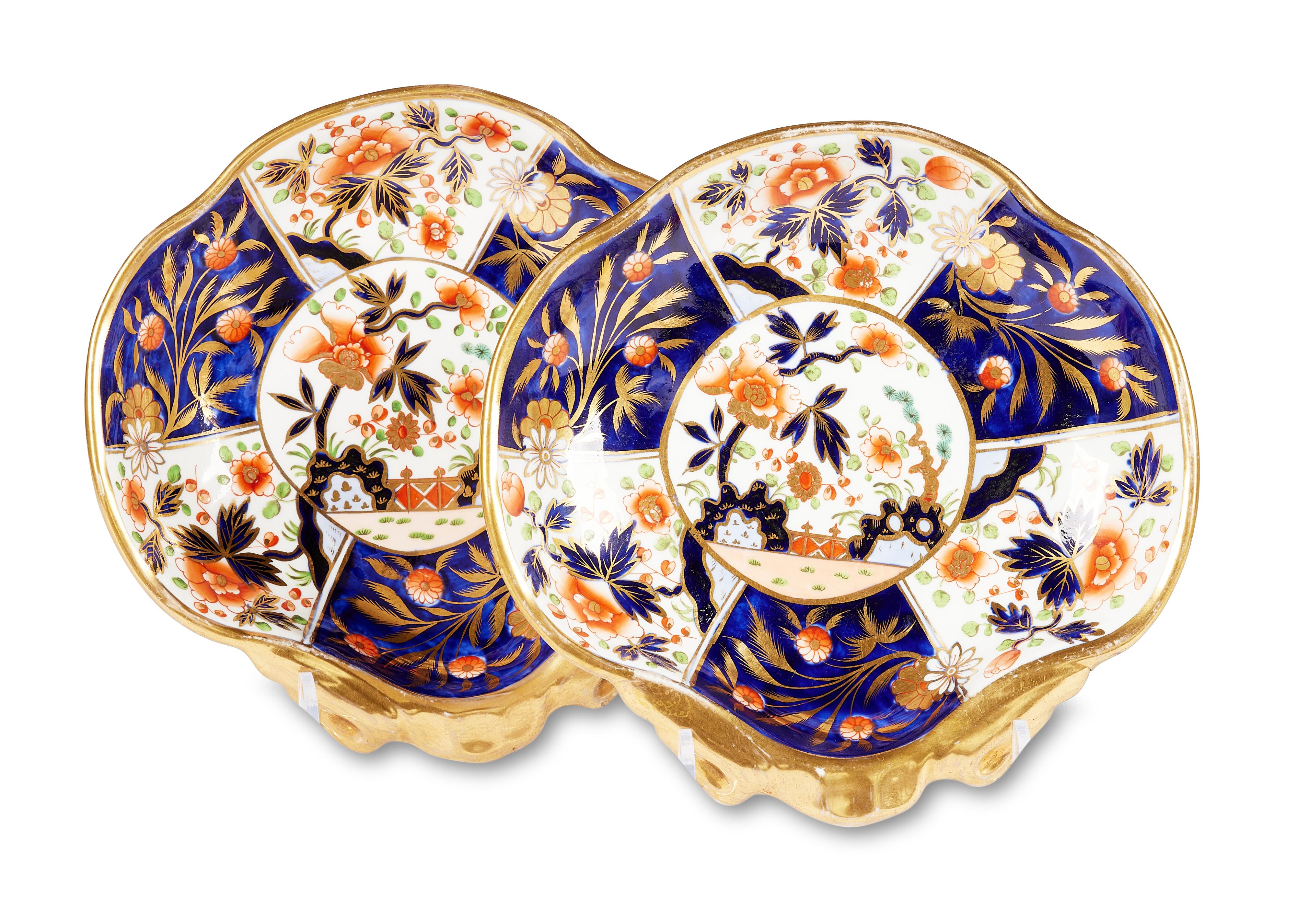 This charming early 19th century Coalport Imari pattern part dessert service comprises of a pair of lidded sauce tureens and stands, a pair of shell shaped dishes and a pair of larger square dishes or plates.

The typical Imari decoration is