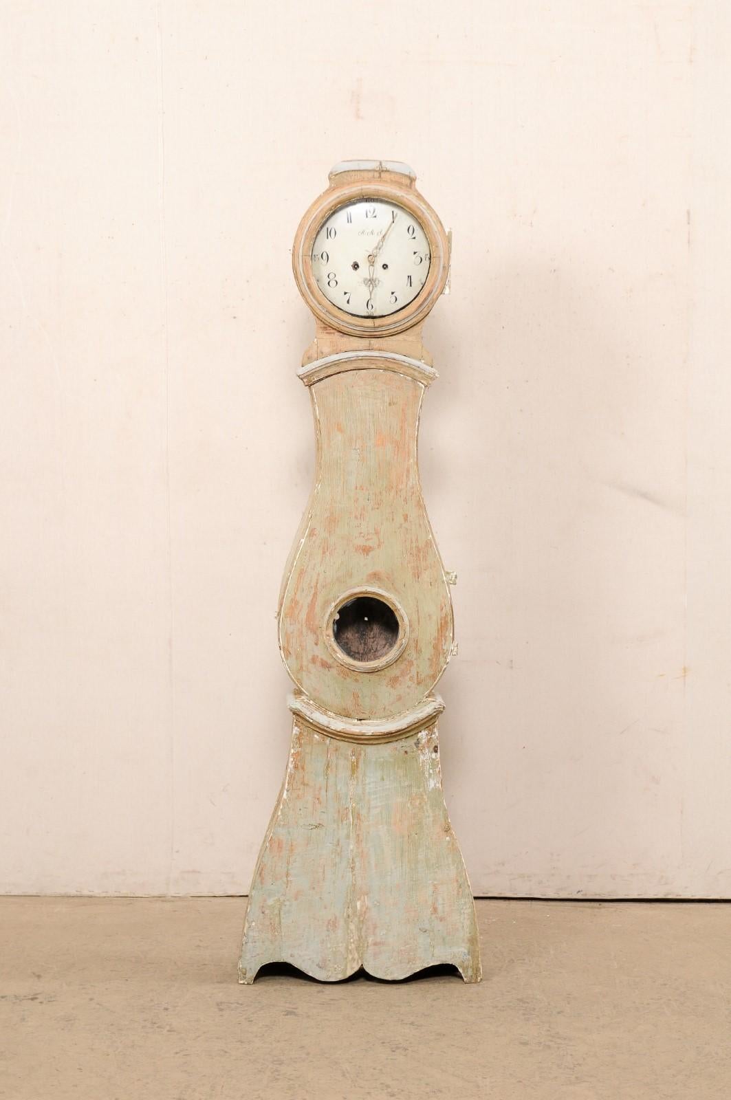 A Swedish carved wood grandfather clock from the early 19th century. This antique floor clock from Sweden features a rounded head, subtly raised crest, and beautiful raindrop shaped body. Curved molding trim accents about the neck and waist define