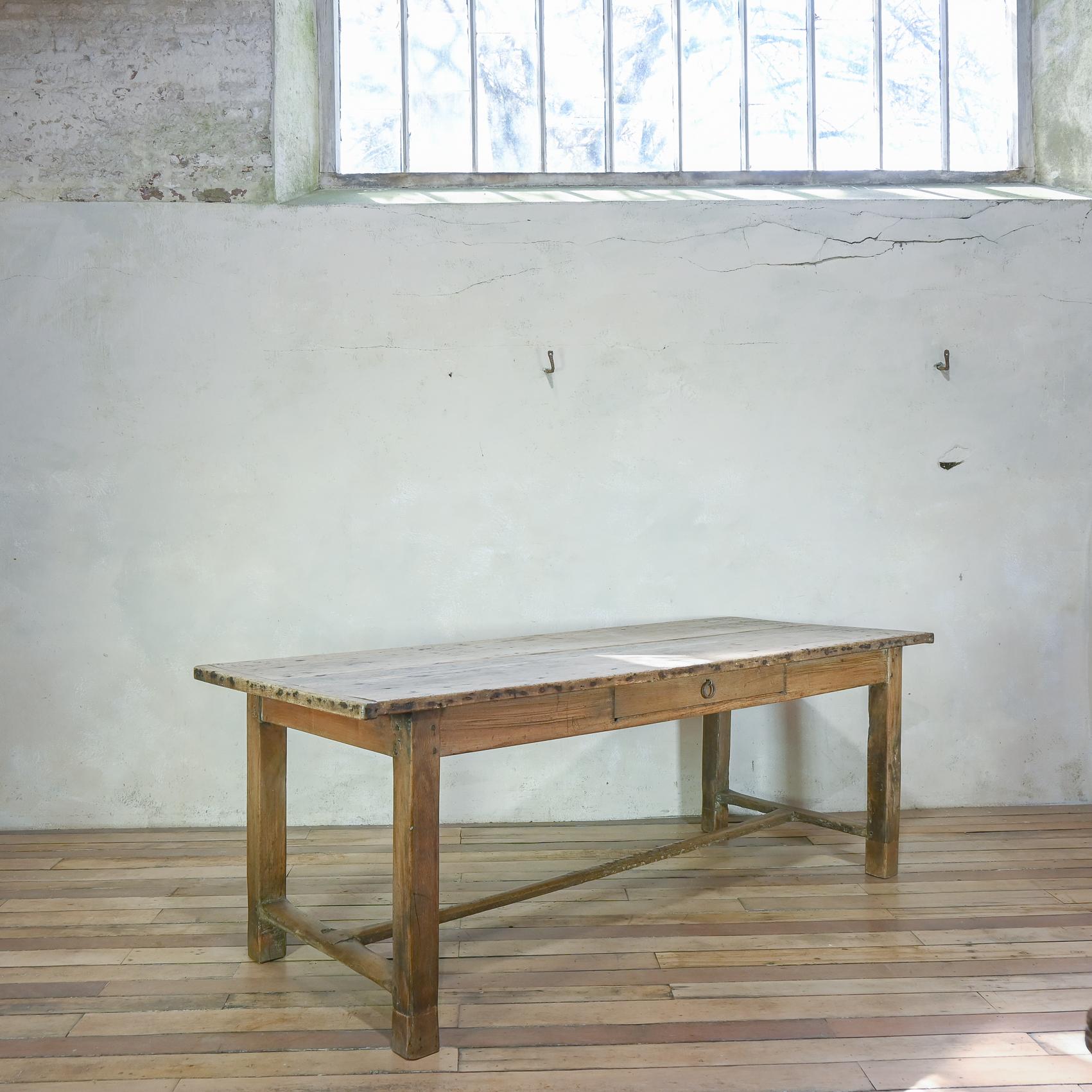 A remarkable early 19th century French sycamore and oak farmhouse table. Displaying a three-plank scrubbed top displaying a wonderful raw patina. Raised on slightly tapered legs united by a stretcher. Demonstrating a faux drawer located on one side