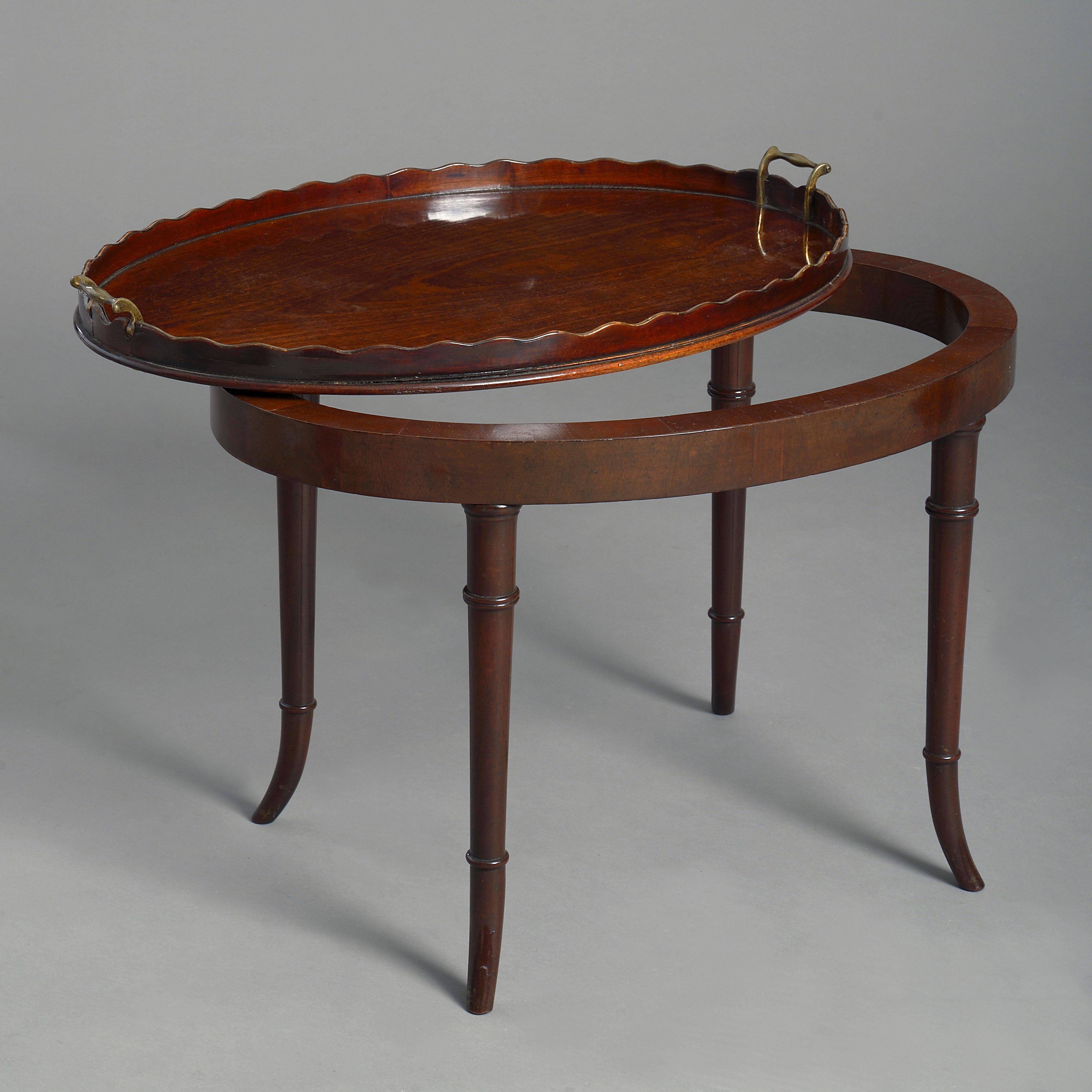 A late 18th century George III period mahogany oval tray, the scalloped galleried border inlaid with boxwood, having shaped brass carrying handles at either end. Now mounted as a low table.