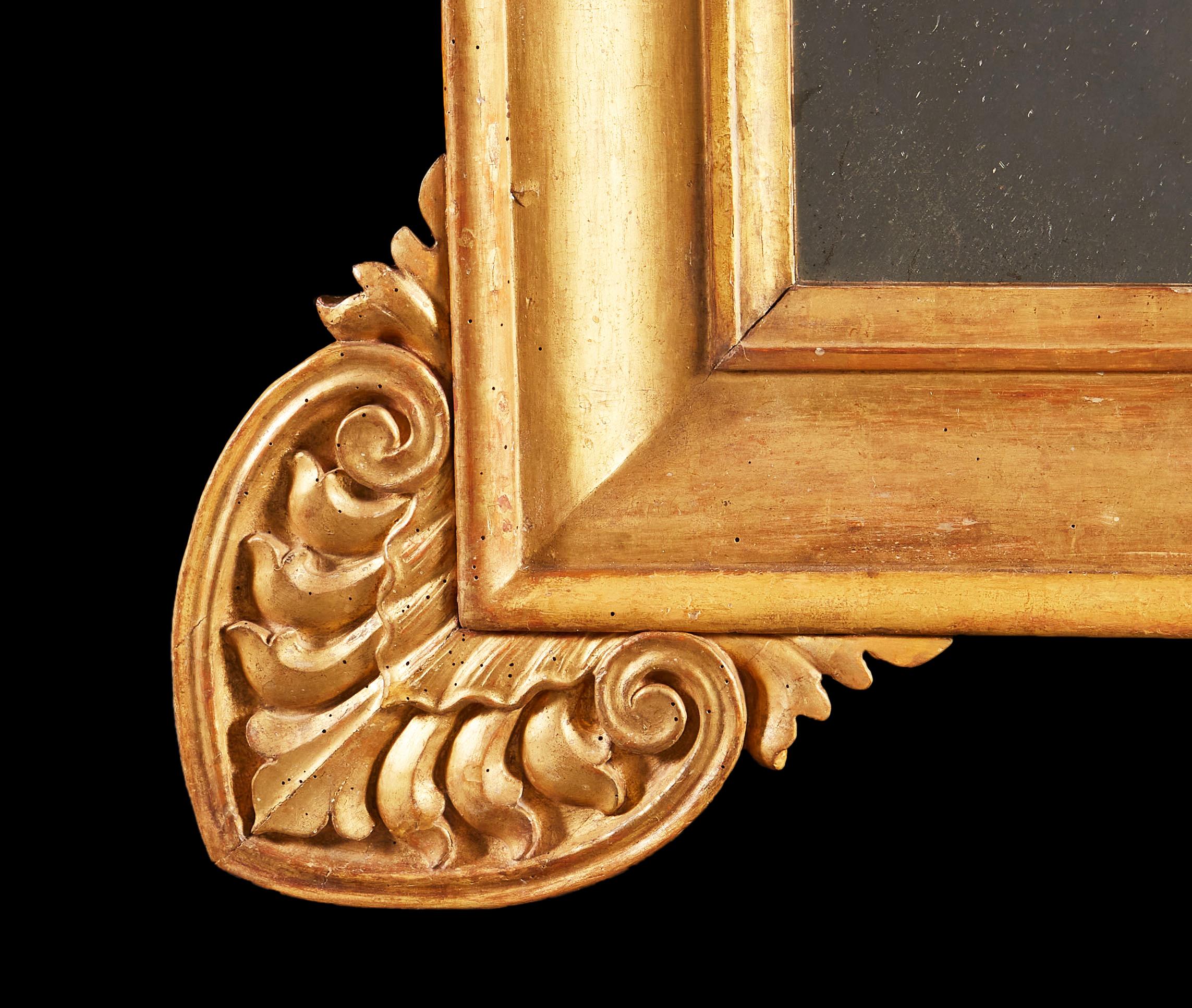 Miroir en bois doré du début du XIXe siècle, de grande taille, avec des hymnes stylisés dans les coins, avec une plaque de miroir au mercure.