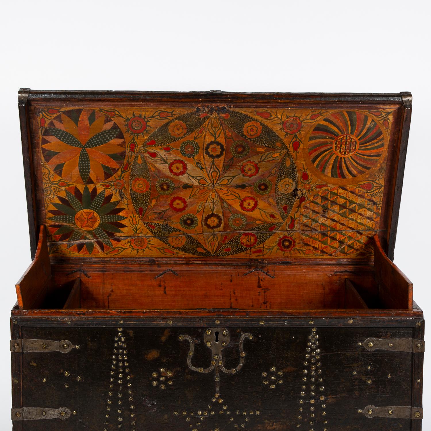 A large early 19th century Northern European painted chest, the exterior decorated with studwork and iron bindings, the interior hand painted with brightly colored floral and geometric designs.