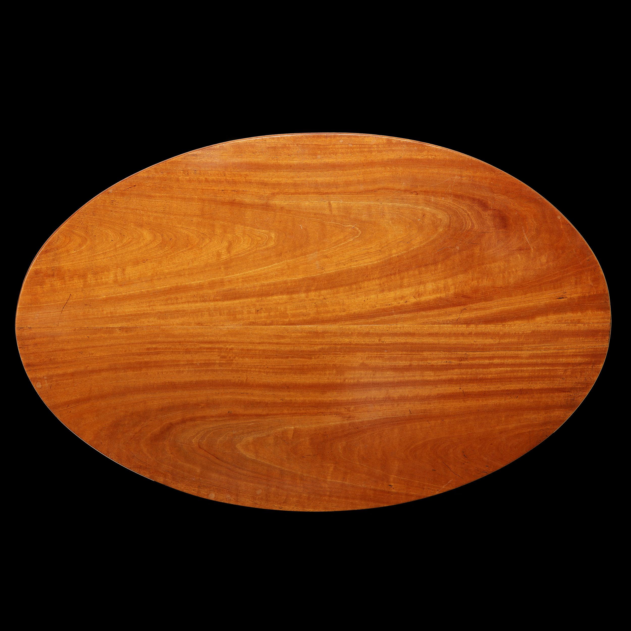 Ein feiner ovaler Tisch aus massivem singhalesischem Satinholz, mit abgeschrägter Kante und gedrechselter Säule, getragen von einem geschnitzten vierbeinigen Sockel.

Höhe     61.50cm  
Breite      61.00cm
Tiefe      35.00cm