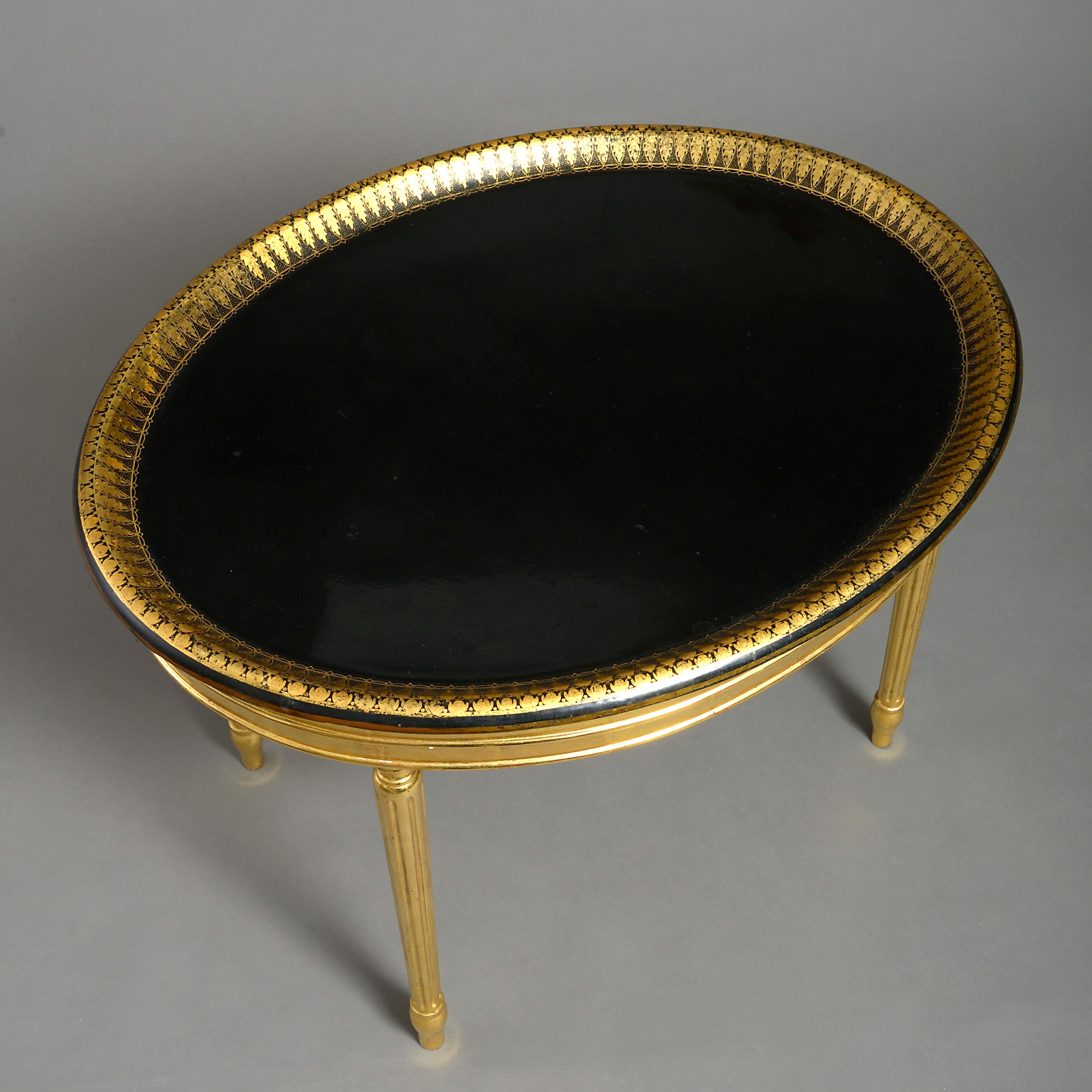 An early 19th century Regency period black and gilt decorated oval tray, set upon a later gilded base with fluted legs.