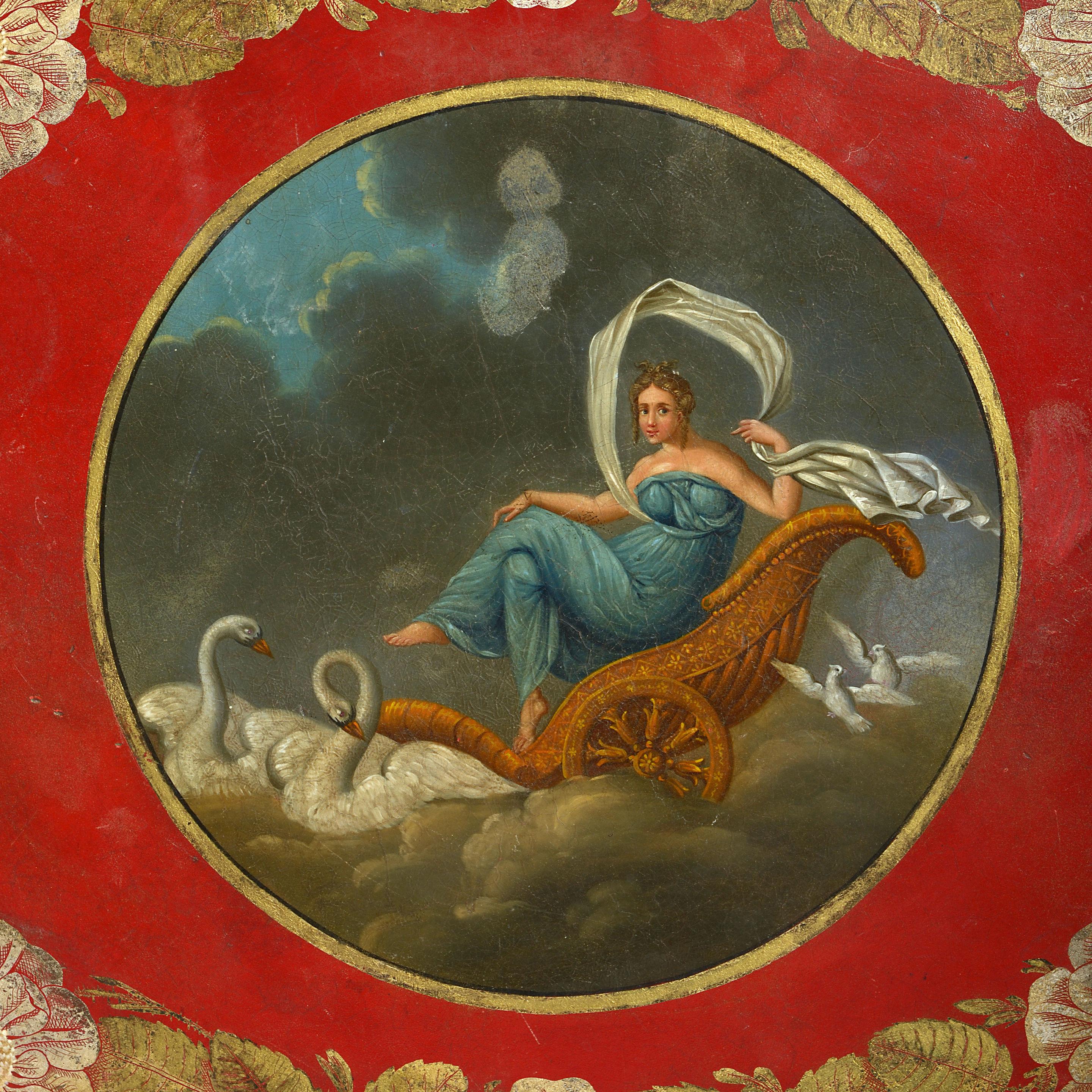 An early 19th century Regency period tole tray with carrying handles, having polychrome and gilded decoration of a female seated upon a carriage with swans, a floral and foliate border, all on a red ground.