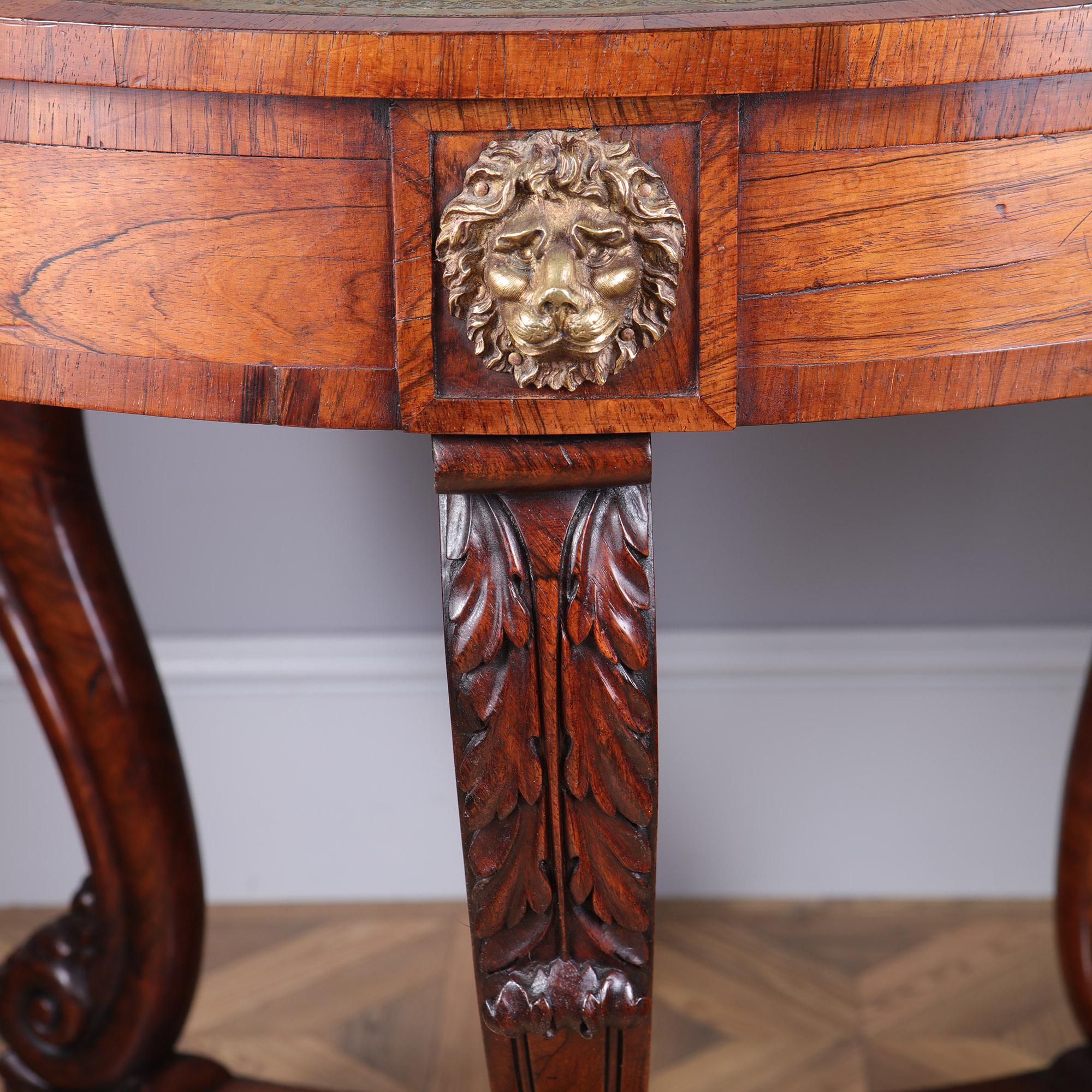 An early, 19th Century Regency rosewood drum table.  The circular top is inset with a green scalloped leather above a frieze with three drawers with brass star handles and interspersed with finely chased lion masks. The top is raised on three scroll
