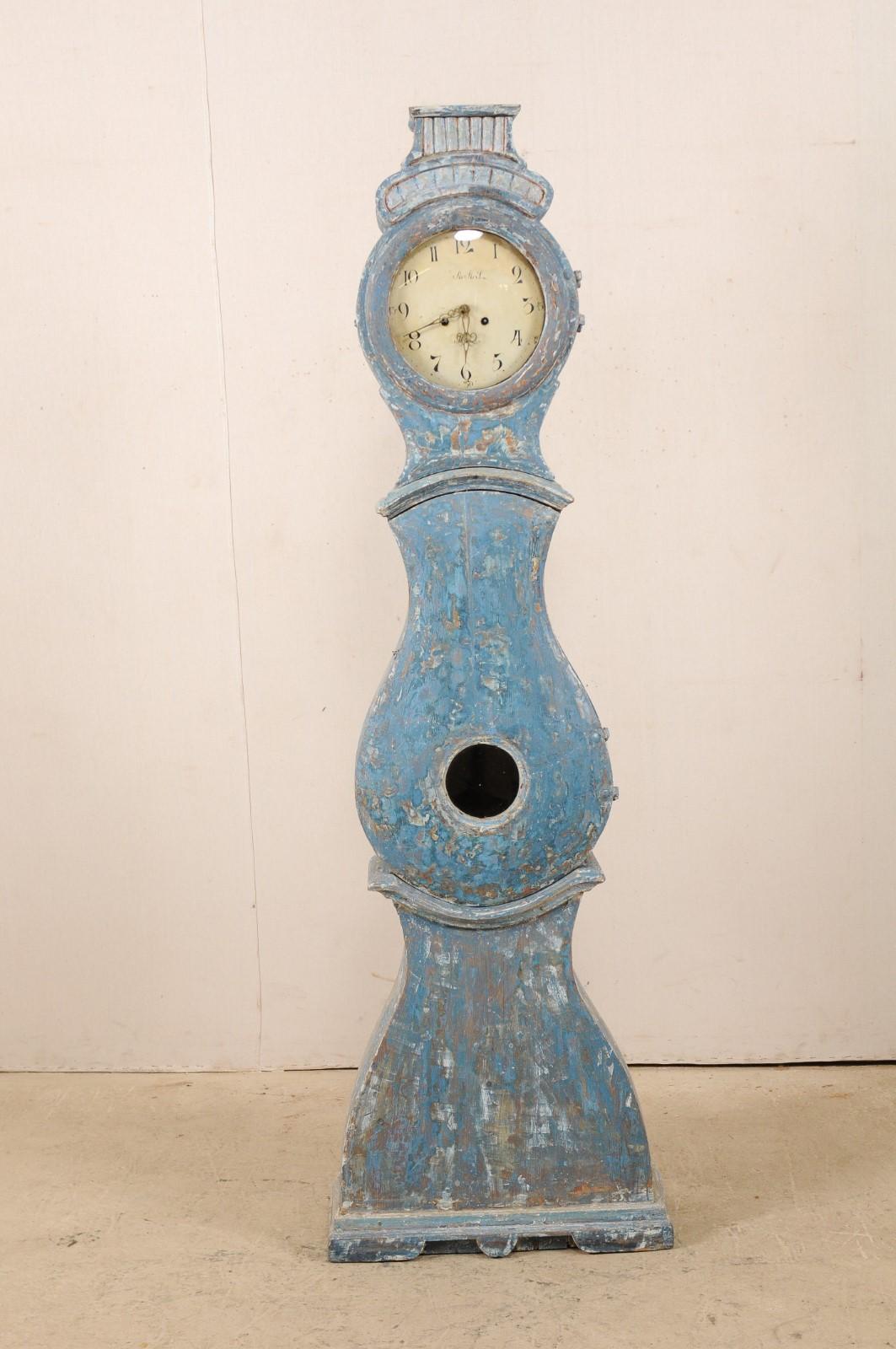 An early 19th century Swedish grandfather clock scraped to its original blue color. This antique tall clock from Western Sweden features a raised bonnet with flattened top, adorned in reeded carvings, atop a round-shaped head, typical tear-drop