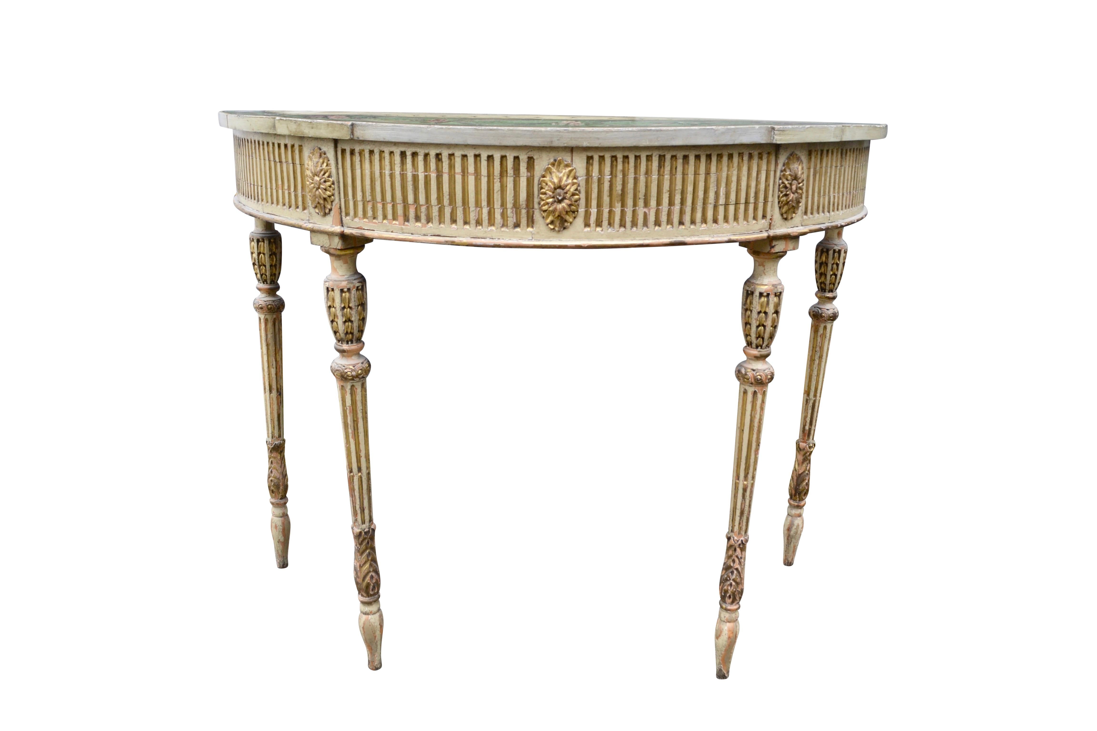 A fine quality late 18thC Adam period demi-lune console table; the entire table is painted a cream colour, the four shaped and tapered legs decorated with gilded wood fillets; the frieze is fluted all round with large gilded patterae above each leg.