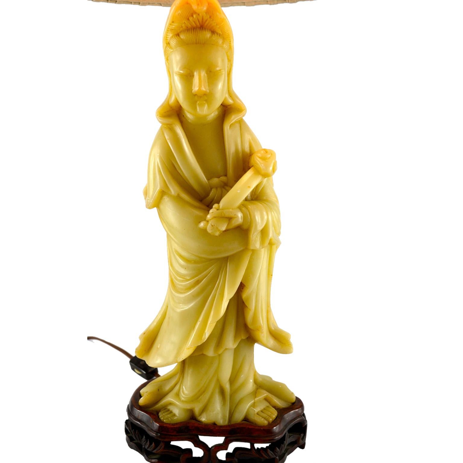 An early 20th century carved soapstone (cream/celery color) lamp of the standing goddess Guanyin presently mounted on a carved rosewood base.