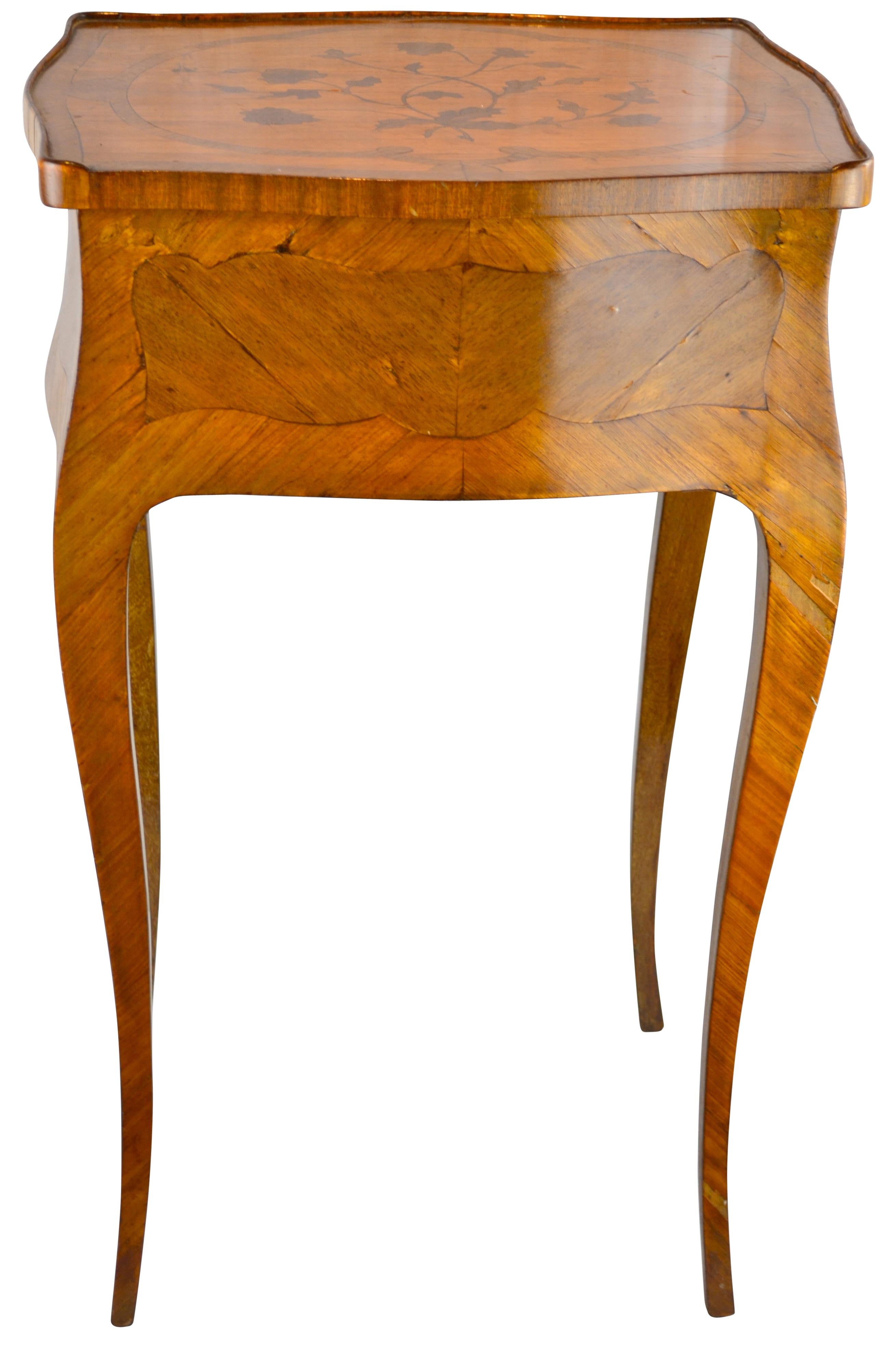 The oak carcass veneered in kingwood and satinwood, with inlaid floral decoration to the galleried top, drawer to one side, on slightly curved legs. 
 