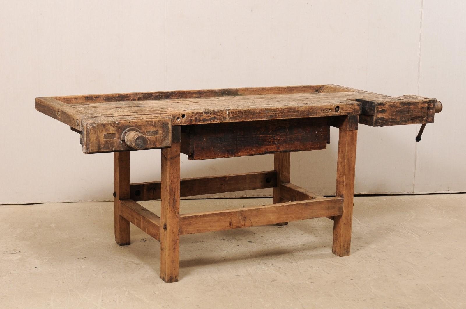 An American work bench table with large drawer from the early 20th century. This antique workbench from Bethlehem, Pennsylvania (as hand-marked at underside) has a thick, rectangular-shaped top with raised lip around all sides, large adjustable