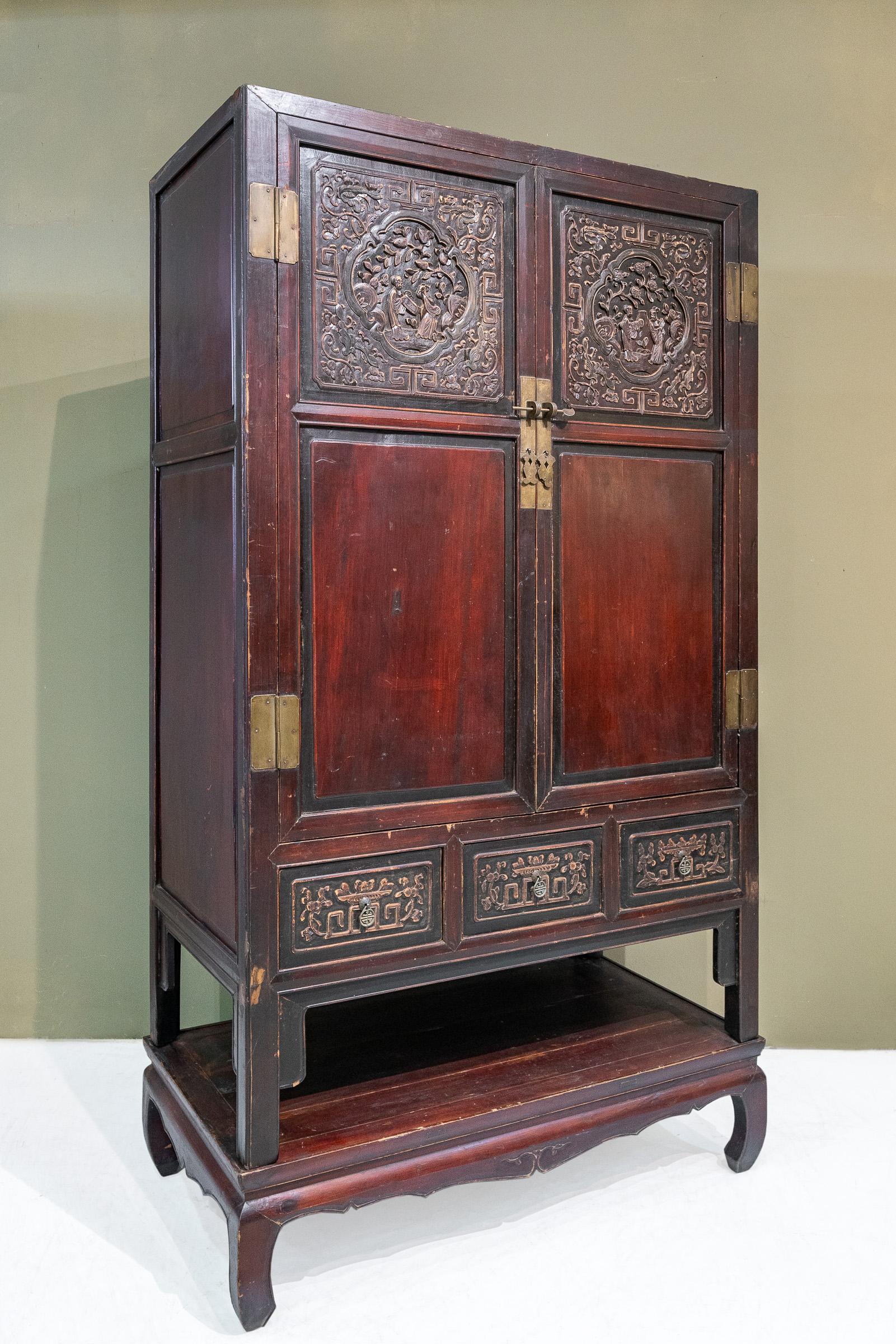 An early 20th century 2-tier cabinet from Shaoxing city, Zhejiang province, China. The carvings on the top part of the doors feature two couples in the garden, one pair is appreciating a painting and another pair is appreciating music. These two