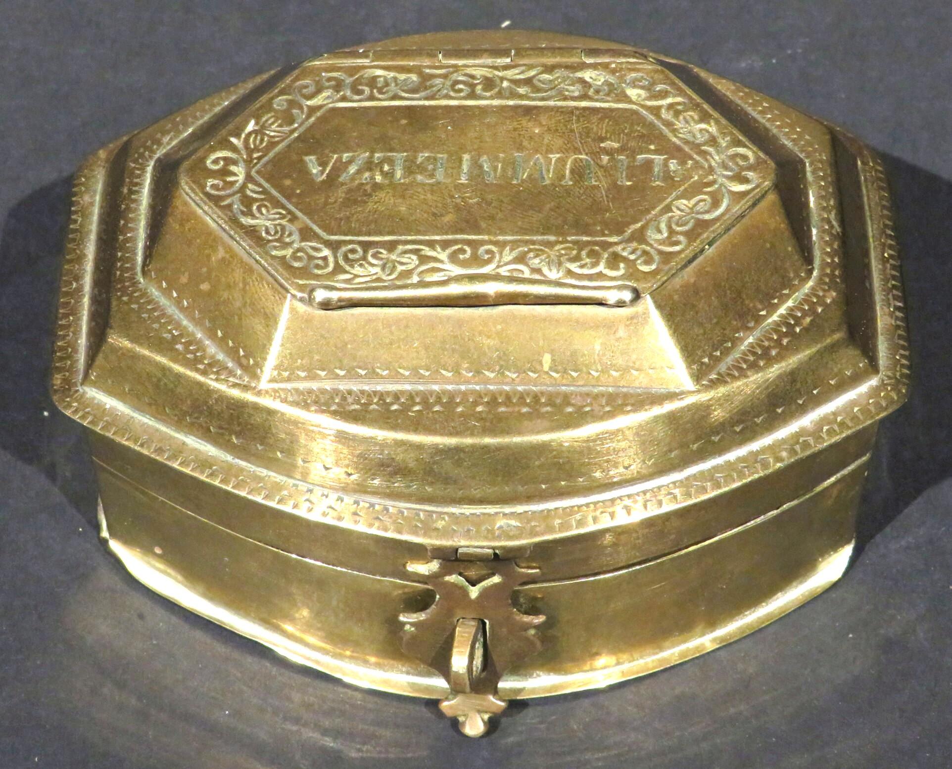 The brass body showing a hinged lid rising up to a faceted receptacle with an engraved  hinged cover, overtop a hinged open compartment which then lifts to reveal an interior fitted with four small compartments surrounding a central compartment with