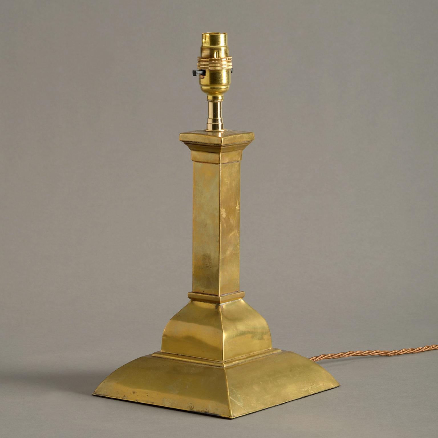 An early 20th century brass table lamp, the square column stem set upon a shaped plinth base.

(Dimensions refer to brass base and exclude electrical components).