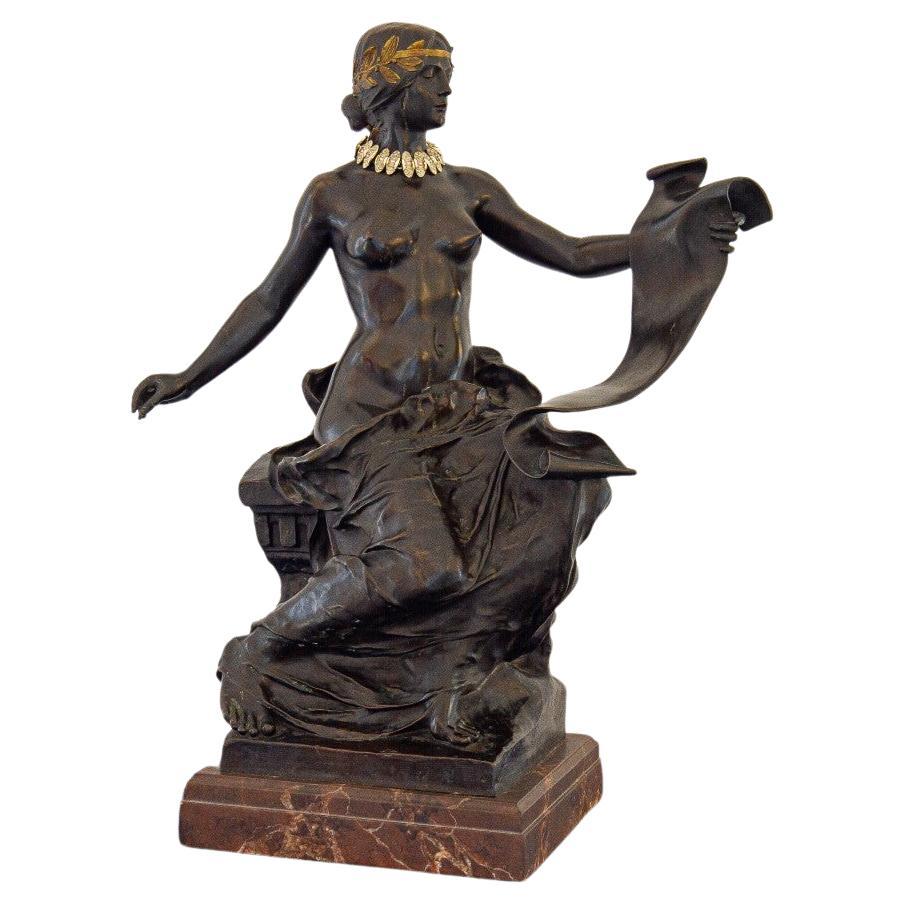 An late 19th century French bronze of an allegorical figure reading a scroll, with a gilt bronze laurel wreath adorning her head mounted on a brown marble base. This sculpture is titled 'L'Histoire' and also known as 'La Poesie', after a sculpture