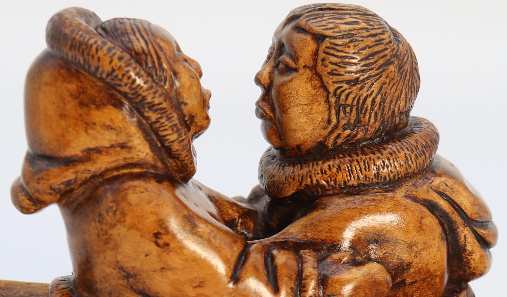 
This superb rare figure group is a piece of Canadian folk art. It is beautifully hand carved in Canadian yellow maple wood, a heavy, dense timber. It depicts two young indigenous people from the Arctic region of Canada in a romantic meeting whilst
