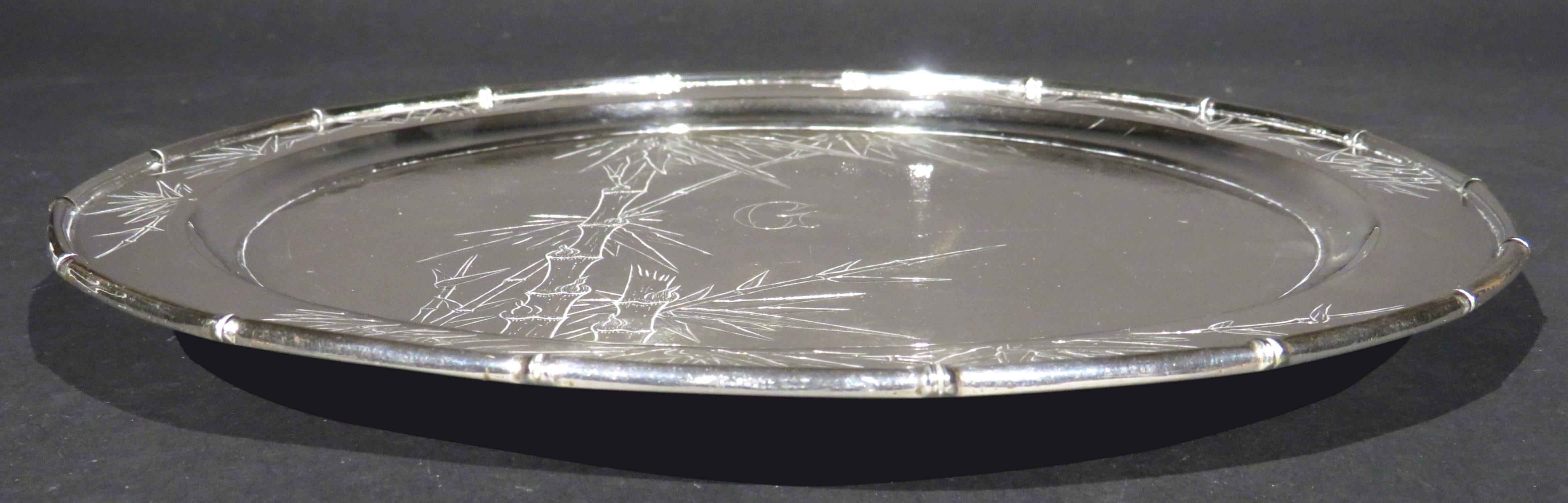 A fine & heavy early 20th century Chinese export silver circular tray / salver having a dished surface engraved with motifs of bamboo branches & foliage against a fine stippled field, rising to a similarly decorated rim with a conforming raised