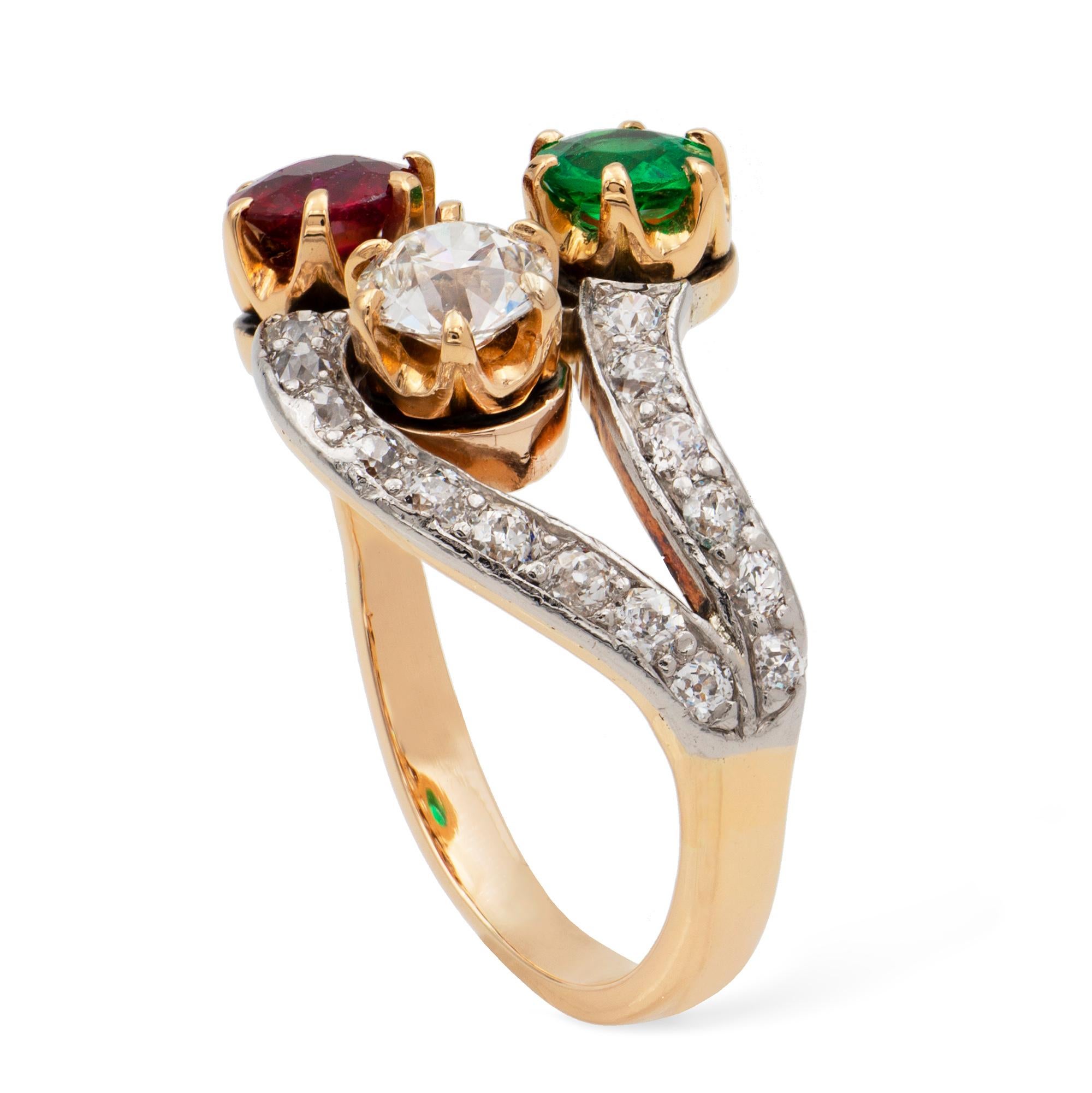 An early 20th century emerald, ruby and diamond triple cross-over ring, the round faceted emerald, weighing 0.25 carats, the round faceted ruby, weighing 0.44 carats and the old European-cut diamond, weighing 0.45 carats, claw set to silver mount