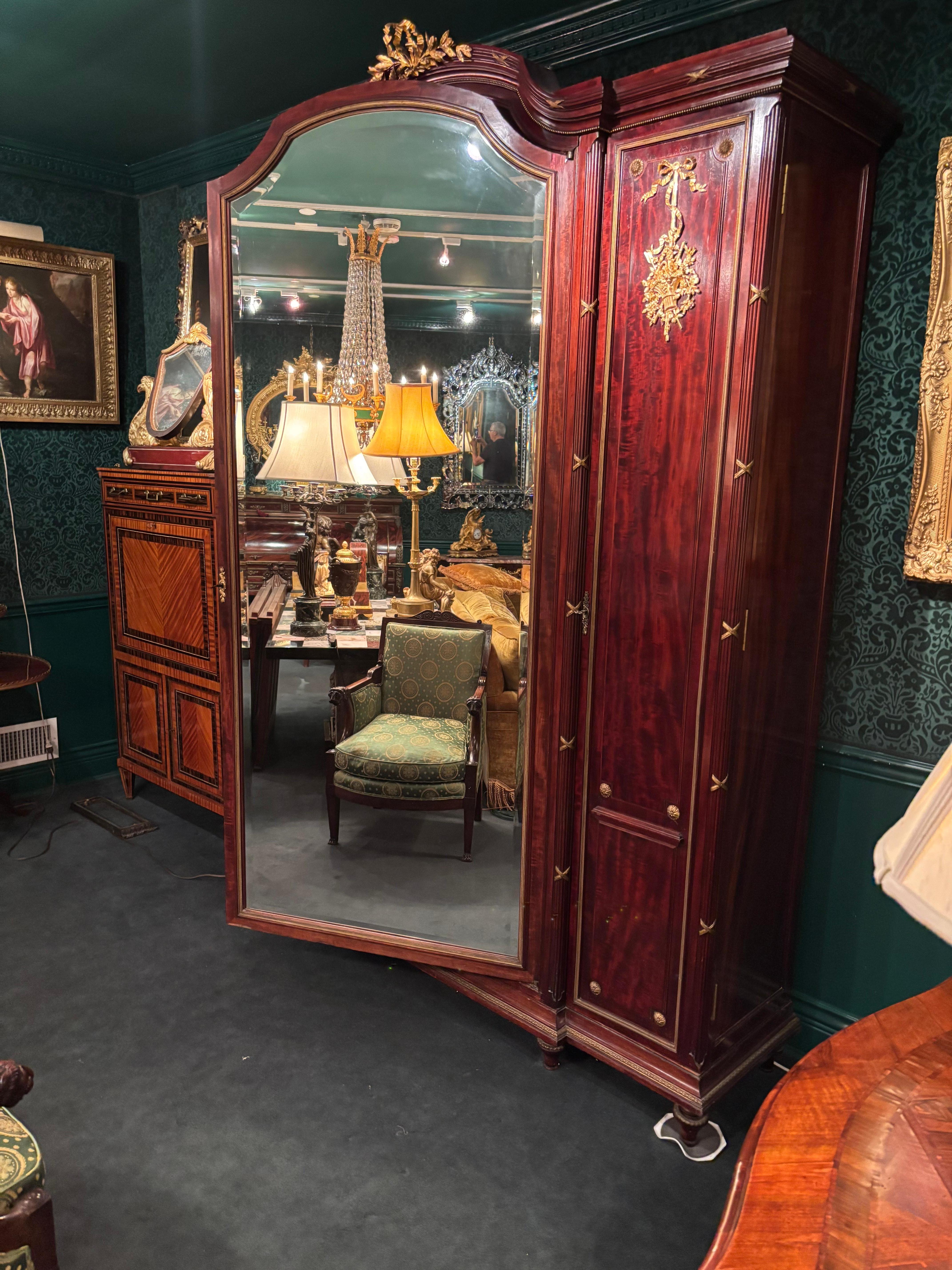 Magnifique objet d'art français du début du 20e siècle.  Armoire de style Louis XVI en acajou et bronze doré à la manière de François Linke.  Le sommet arqué est centré par une couronne de laurier en bronze doré au-dessus d'une grande porte centrale