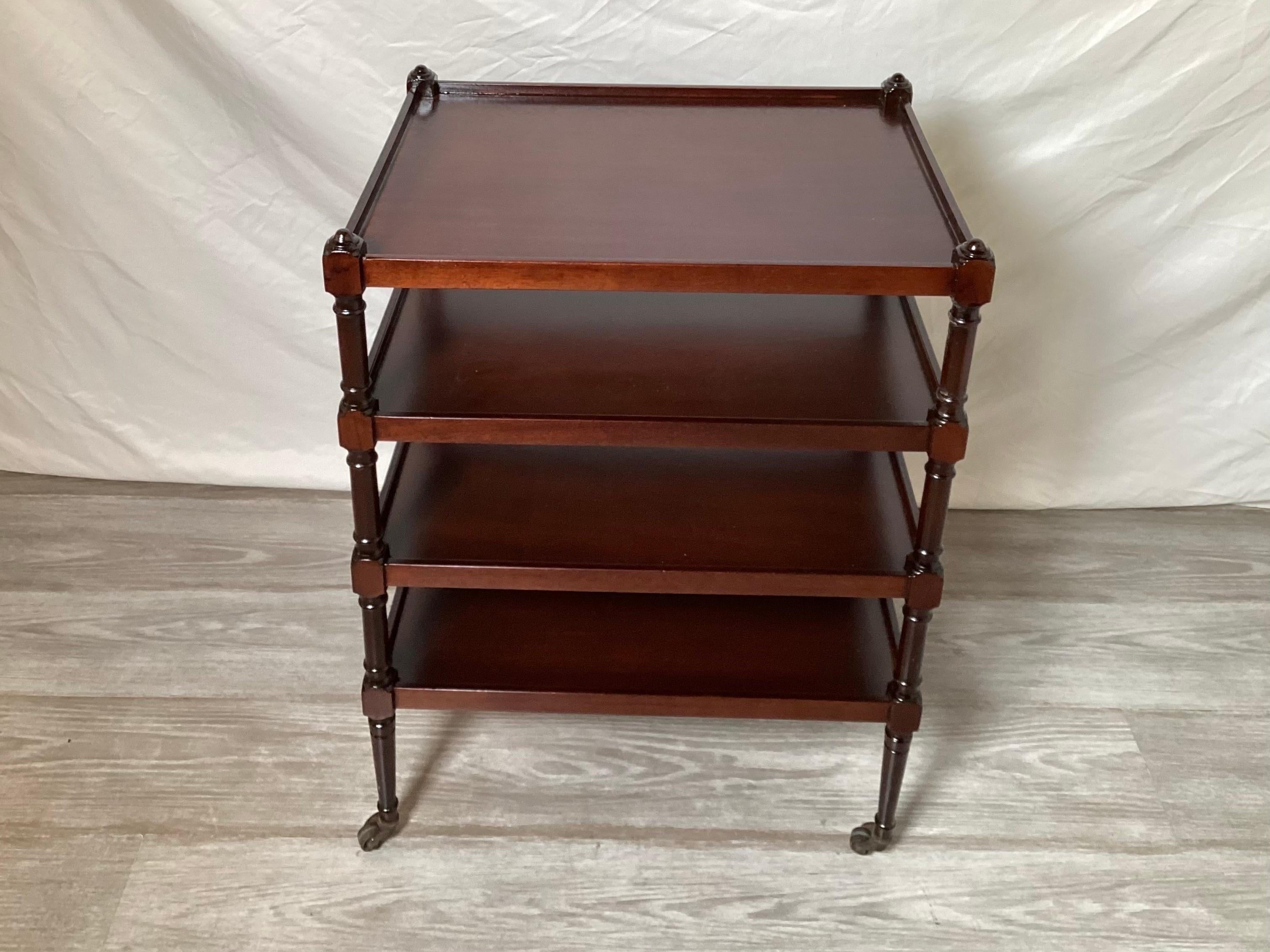 Elegant mahogany four tiered rectangular side table with original patinated brass castors. The table with plenty of storage and display area with four turned legs with low gallery edge on each shelf.