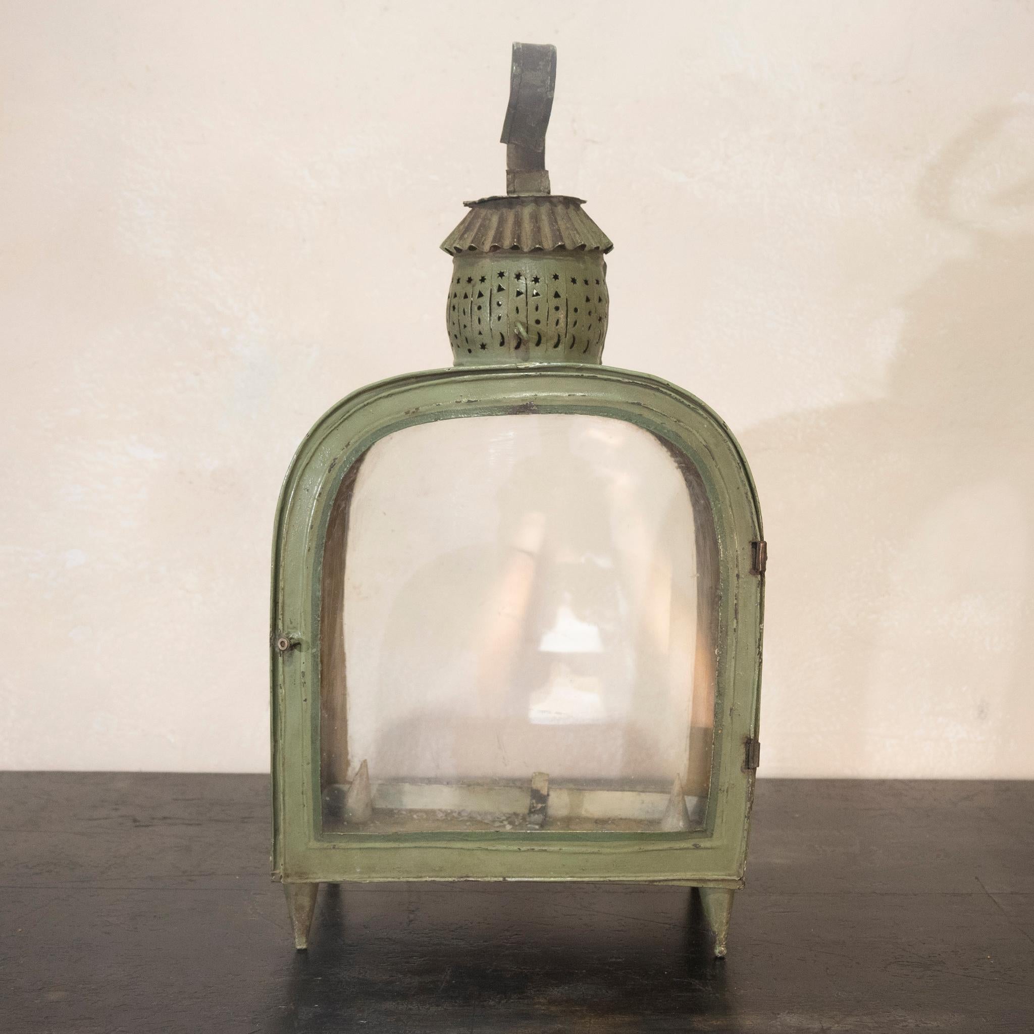 A charming 20th century French green toleware lantern, with pierced decoration in the form of stars and circles. Raised on cone-shaped feet with arched glazed windows and a door. 
 
Measures: Height - 48cm
Width - 25cm 
Depth - 13cm.