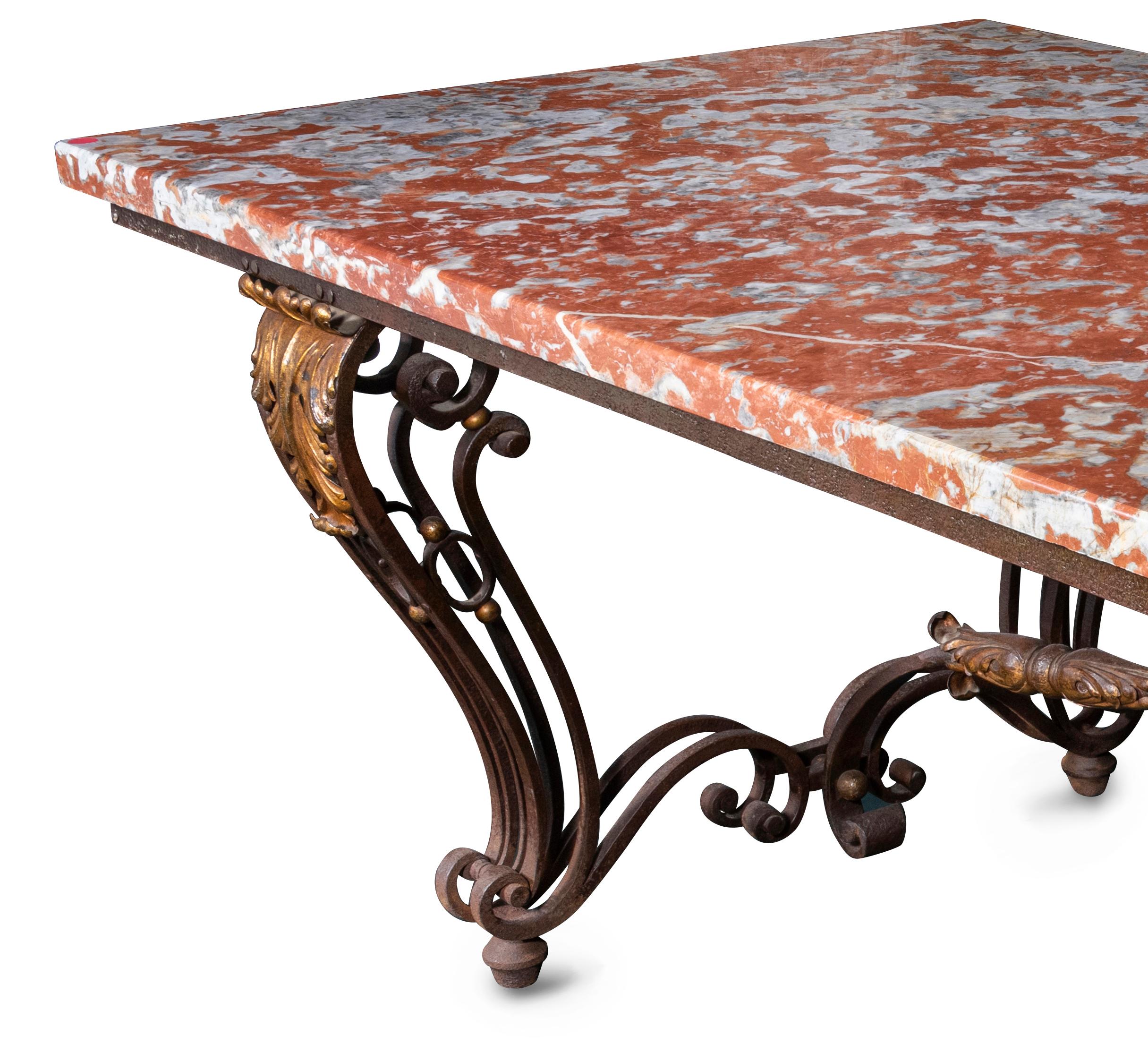 The orange et gris marble top over wrought iron base with pair of cabriole scroll legs, each with gilt anthemion capital and double s-scroll stretchers joined by a central pair of cross s-scroll irons, each with conforming gilt metal anthemion. The