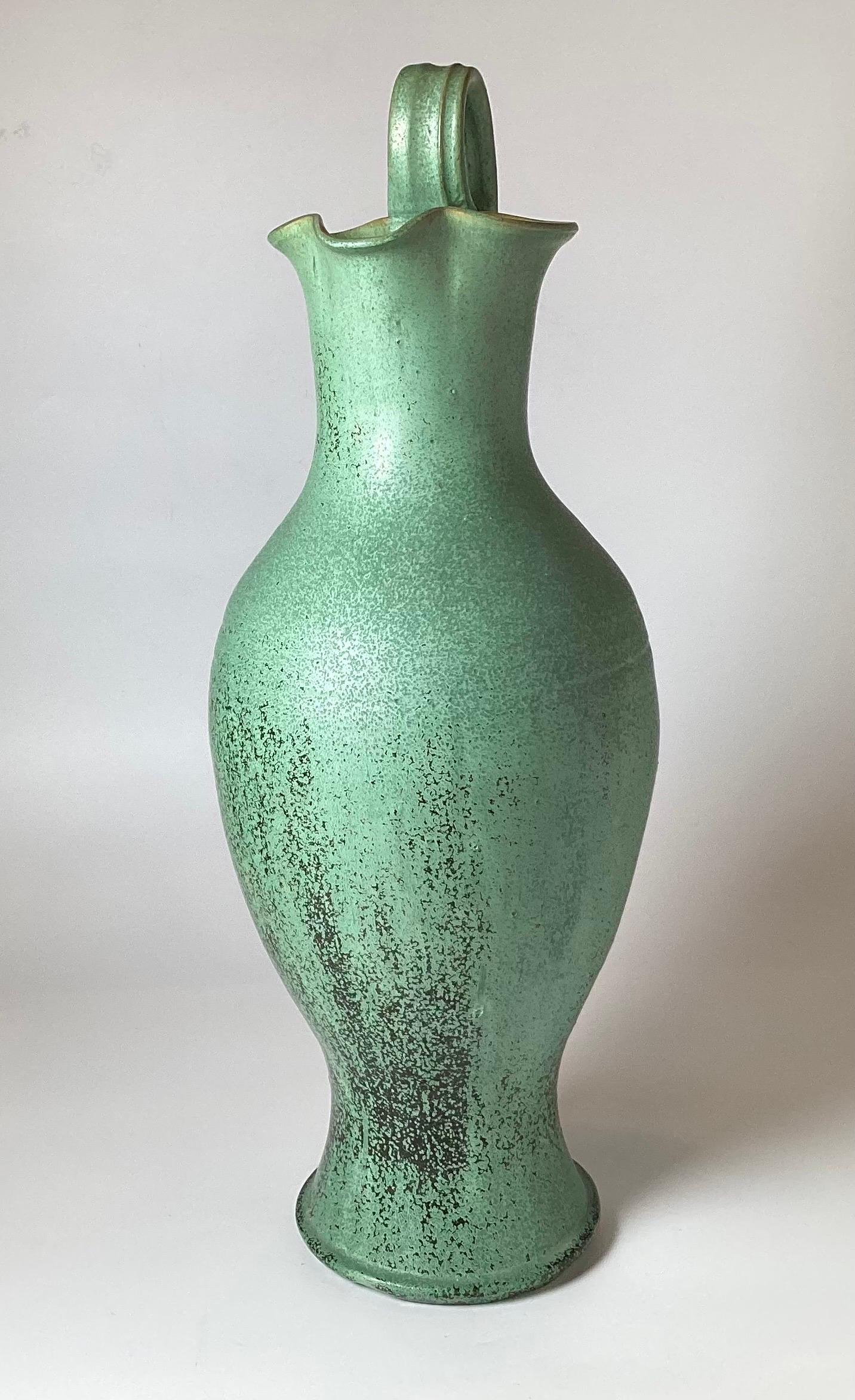 Elegant Verdi green glazed Grecian style terra cotta ewer, circa 1920s measuring 27 inches tall, 11 inches diameter. The green and black glaze with a stippled effect in a jade green color.
