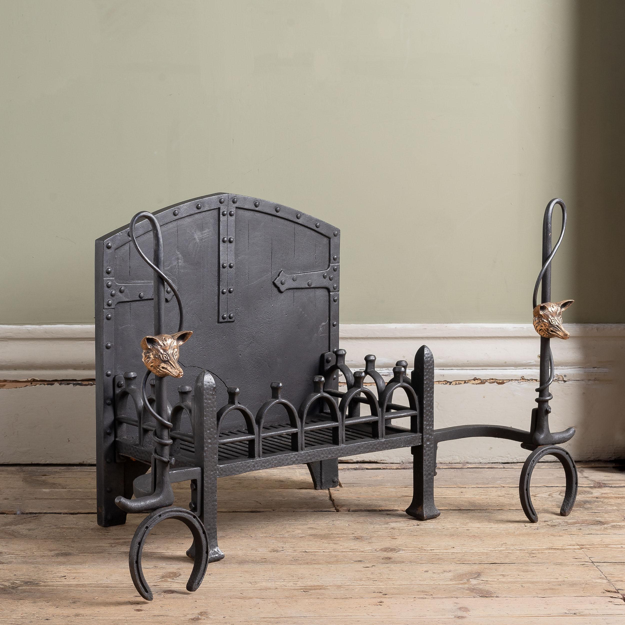 An early twentieth century iron and bronze fire grate, circa 1920s, the standards composed of hunting whips, horse shoes and fox-head mounts.

Dimensions:	55cm (21¾