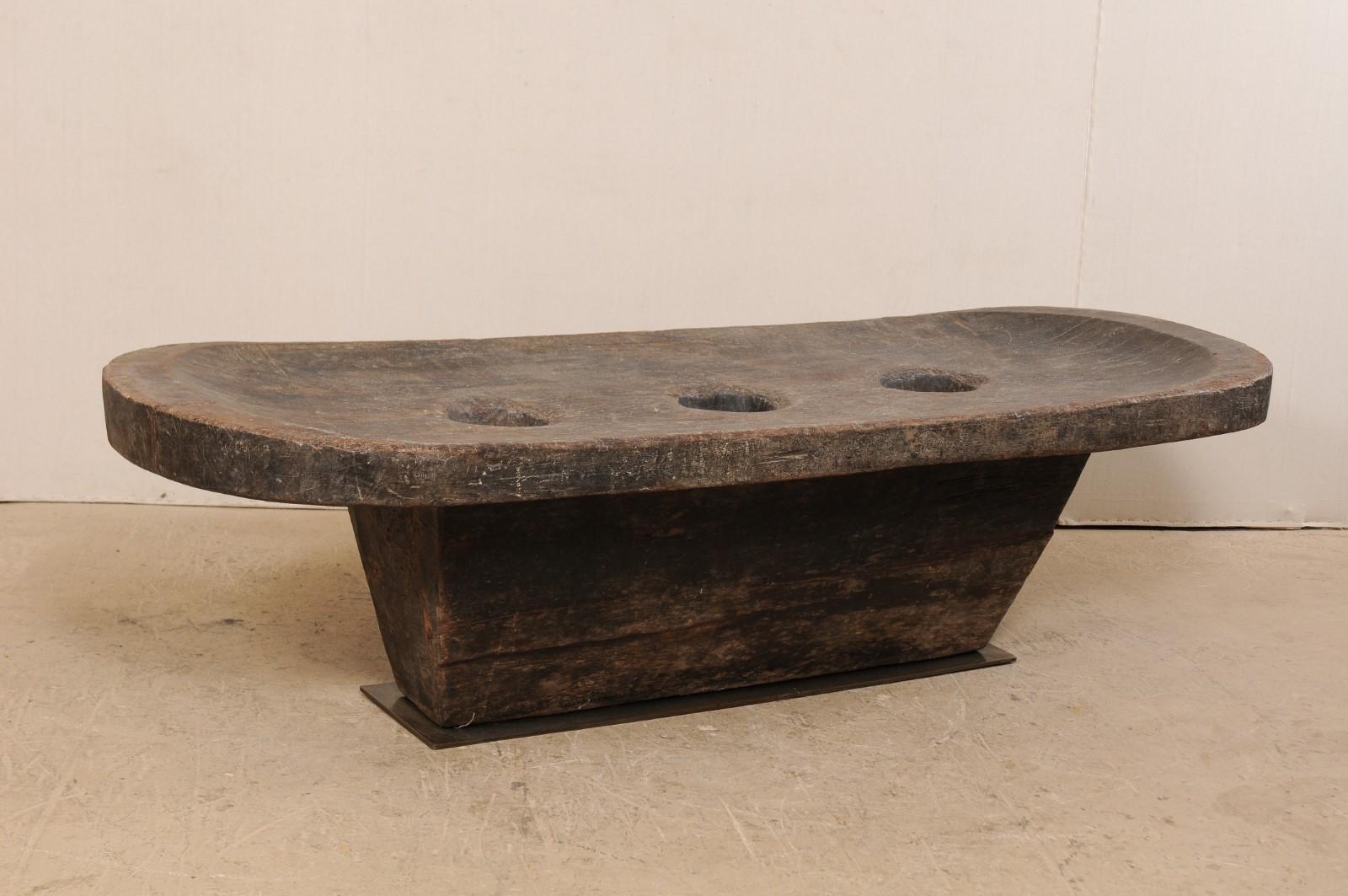 A beautifully rustic Naga wooden table from early 20th century. This antique table from Nagaland, India was originally use by the Naga tribes of North East India as a grinding table, for grains such as millet. The three holes within the center are