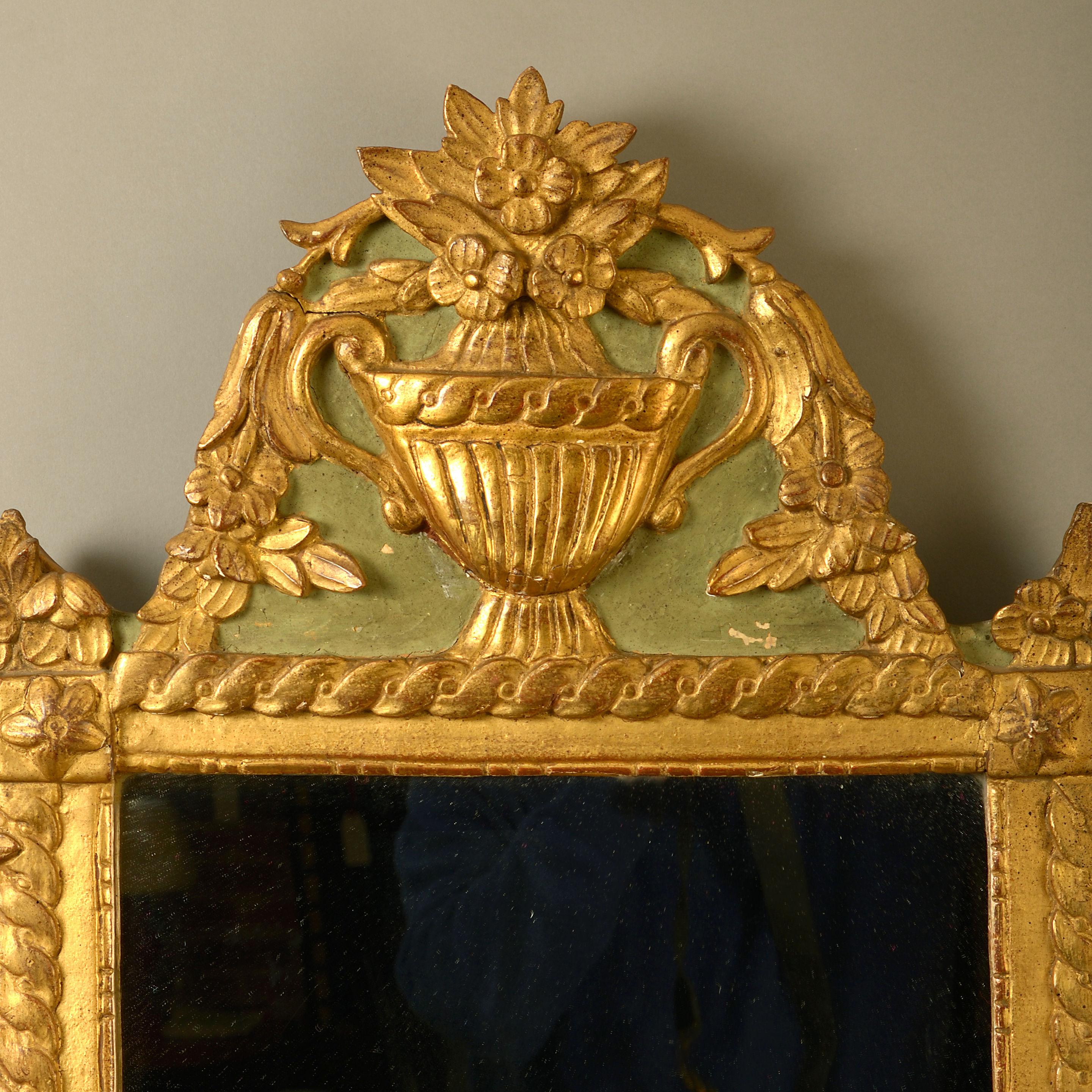 A late 20th century painted and parcel gilded mirror in the early Louis XVI taste, the rectangular frame surmounted with a classical urn.