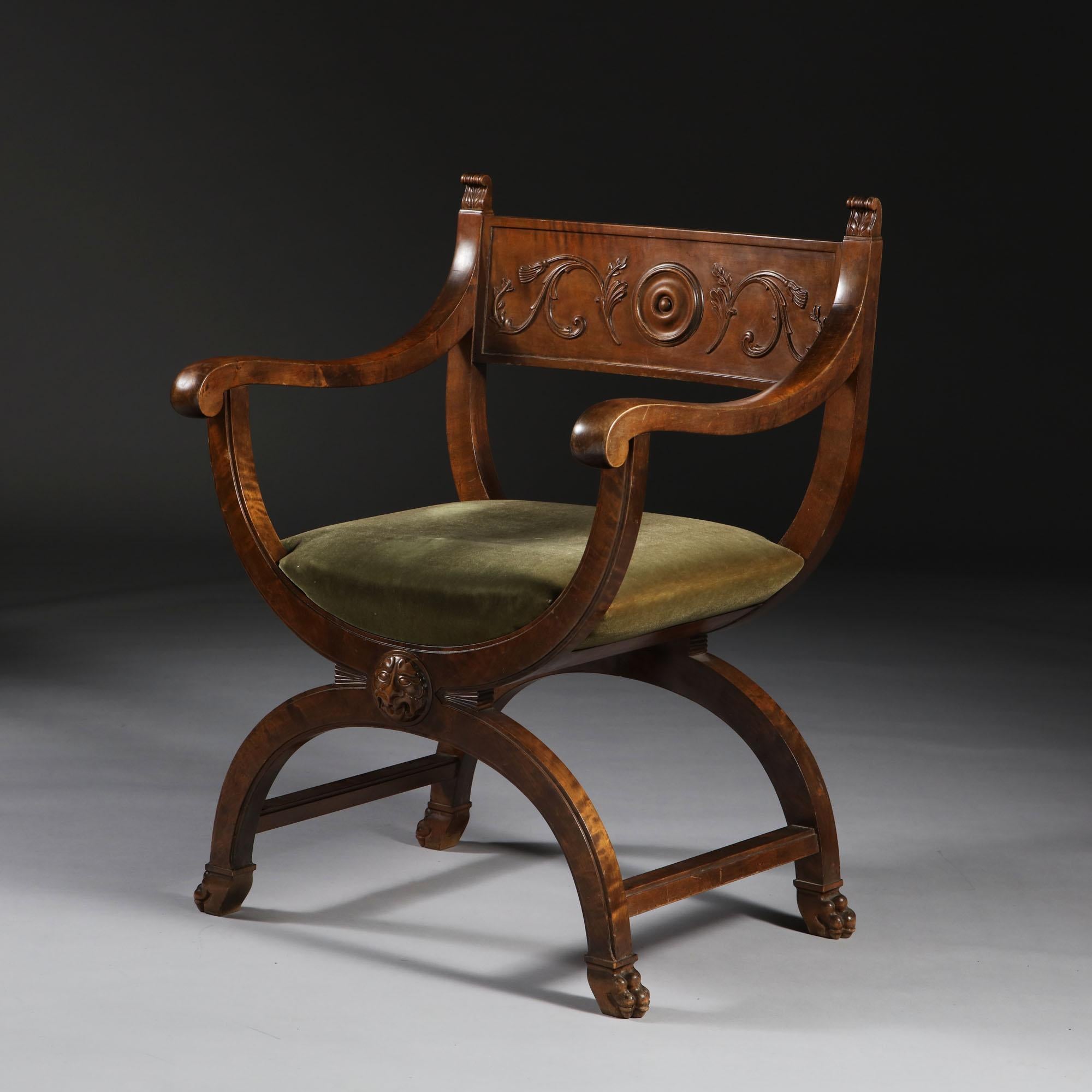 A fine Swedish stained birch X-frame armchair, with central medallion surrounded by scrolling carving to the back, surmounted by carved acanthus leaf finials, with scroll arms and a lions mask to the front cross bar, all supported on four hairy paw