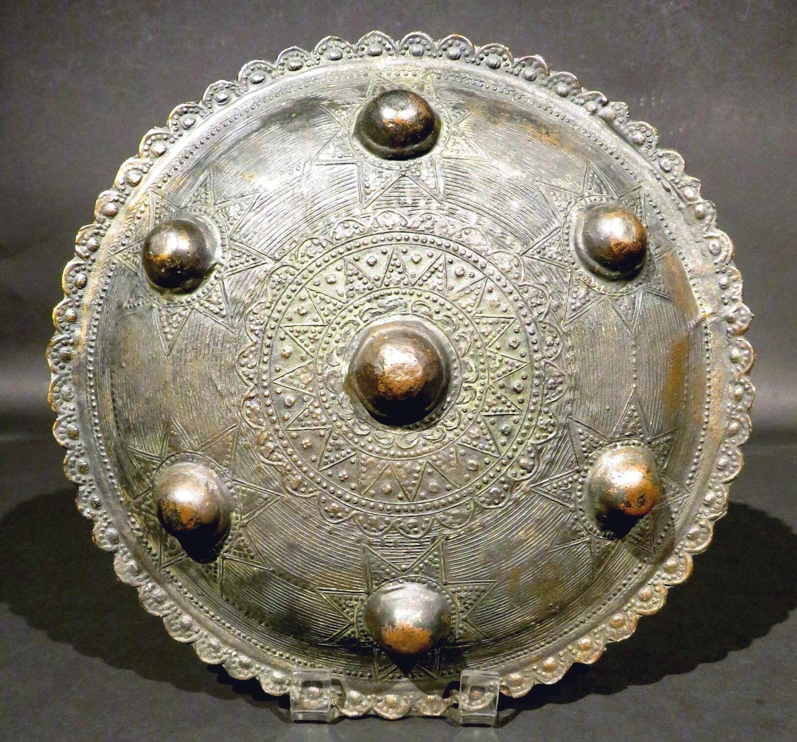 From the North Sumatran region of the Acehnese people, the convex exterior surface showing seven semi-spherical protrusions or bosses centring Islamic inspired star motifs, the reverse showing four eyelets intended for attaching a hand-held strap.