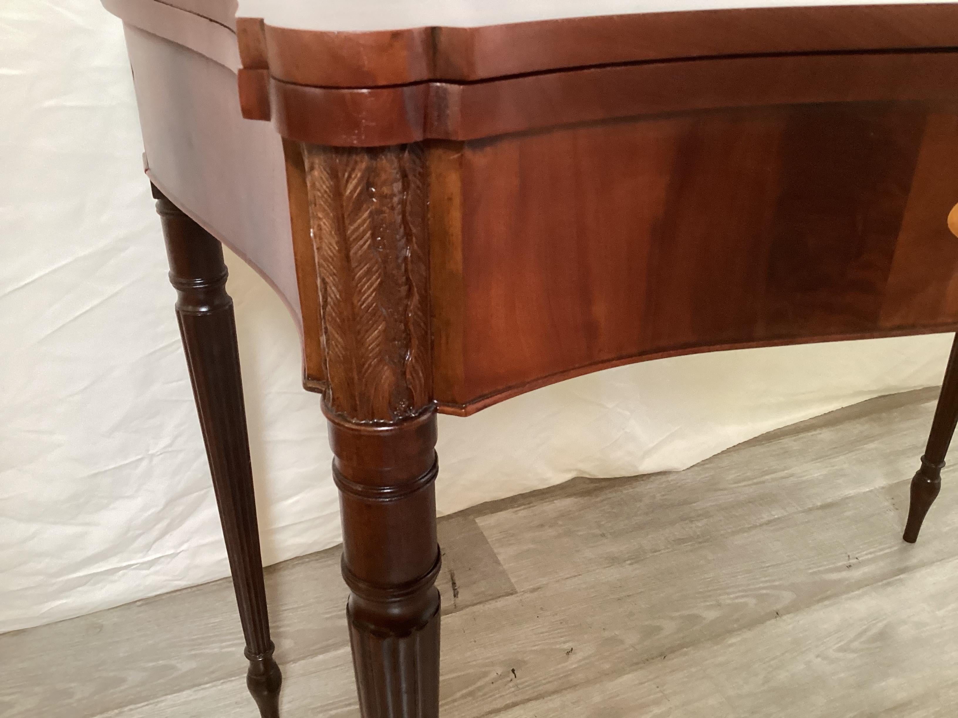 Un bellissimo tavolo da gioco d'epoca Feder con un piano ben sagomato.  Il mogano a fiamma, con graziosi intarsi in legno di raso e capitelli intagliati a mano sulle affusolate gambe scanalate.  Il tavolo si apre a ribalta fino a raggiungere i 36
