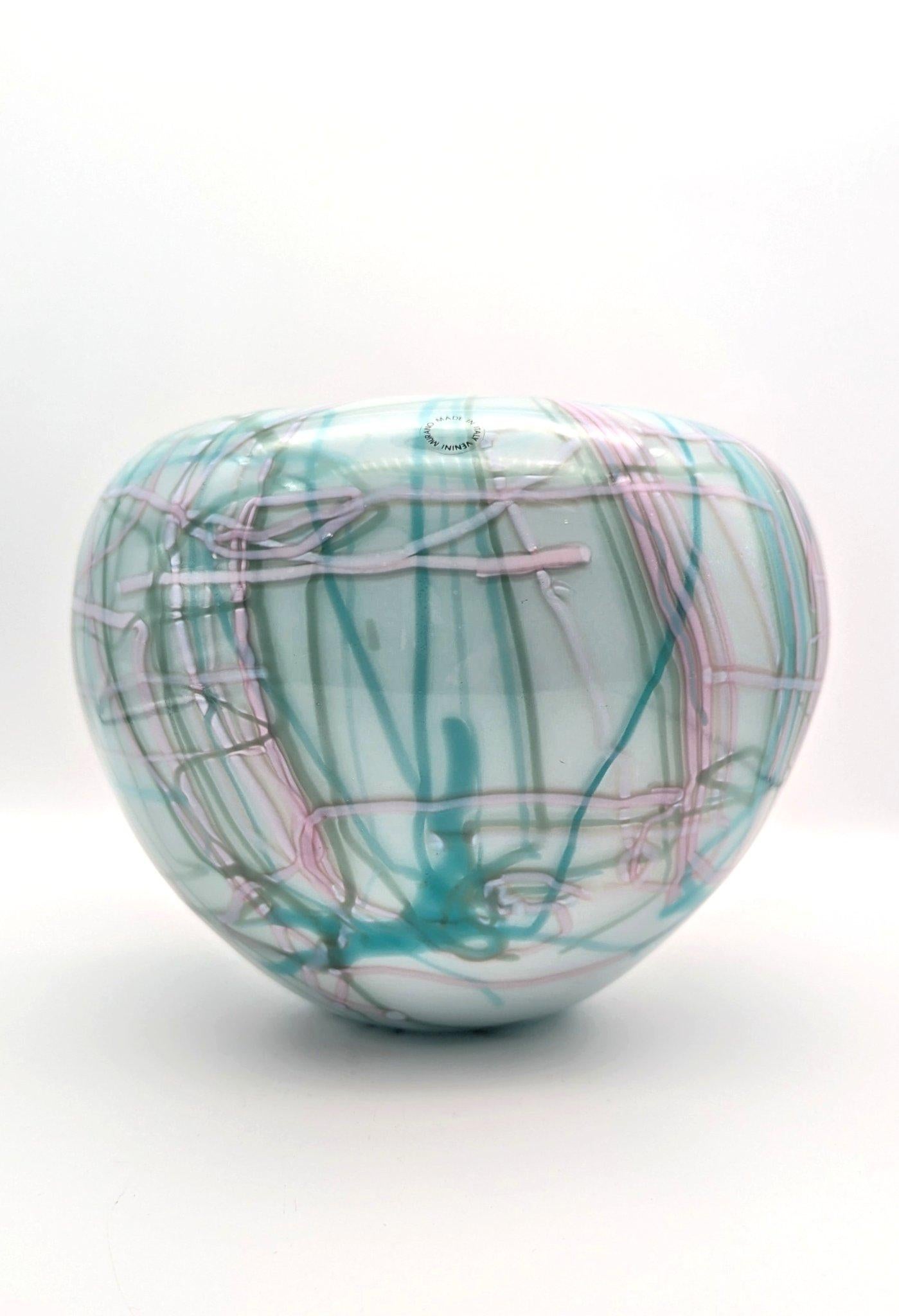 Disegnato da Toots Zynsky nel 1984 per Venini, questo particolare esemplare è stato realizzato nel 1989. Il vaso è stato incamiciato con uno strato esterno di lattimo e uno interno di menta. Canne policrome, che ricordano i pezzi in filet de verre