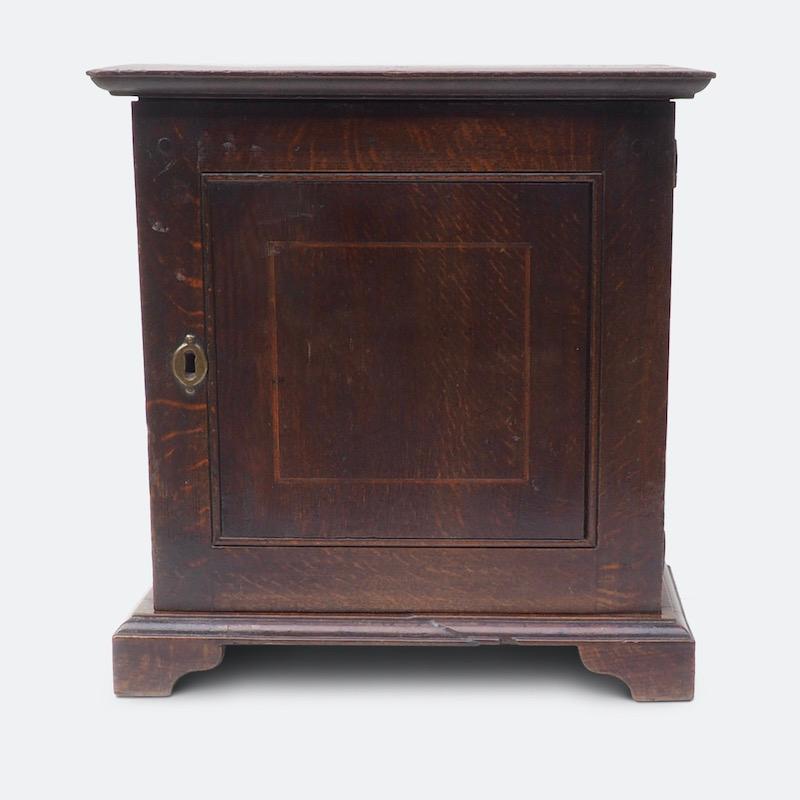 An early George I oak table top spice cupboard, circa 1715

A solid topped oak spice cupboard with a fruitwood inlaid cupboard door enclosing eight small drawers, set on bracket feet.
Lockable and portable small cupboards such as these were