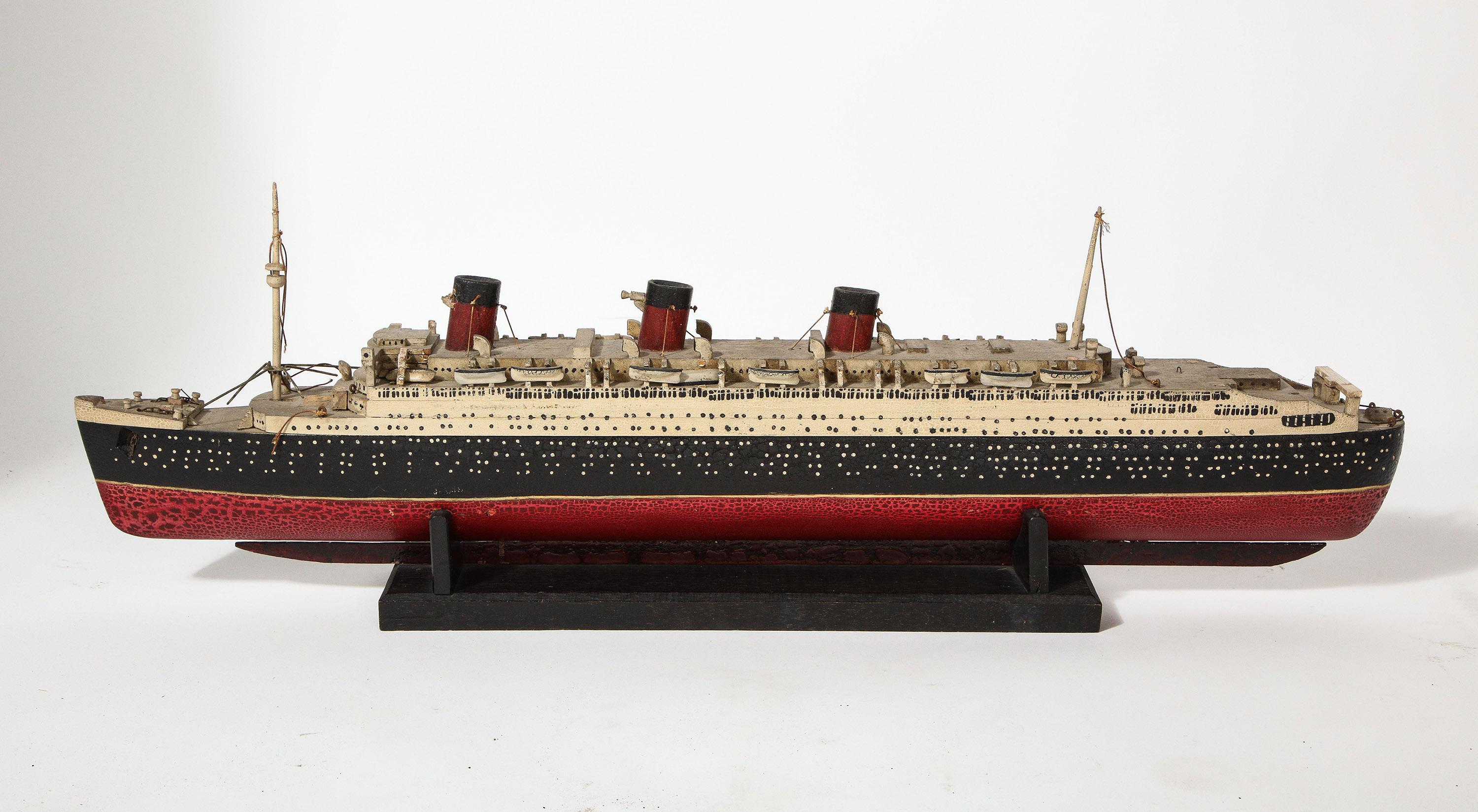 Une maquette ancienne (probablement à la fin des années 1930) du RMS Queen Mary, entièrement sculptée et peinte à la main dans les moindres détails. L'état est assez bon avec une patine d'origine intacte.