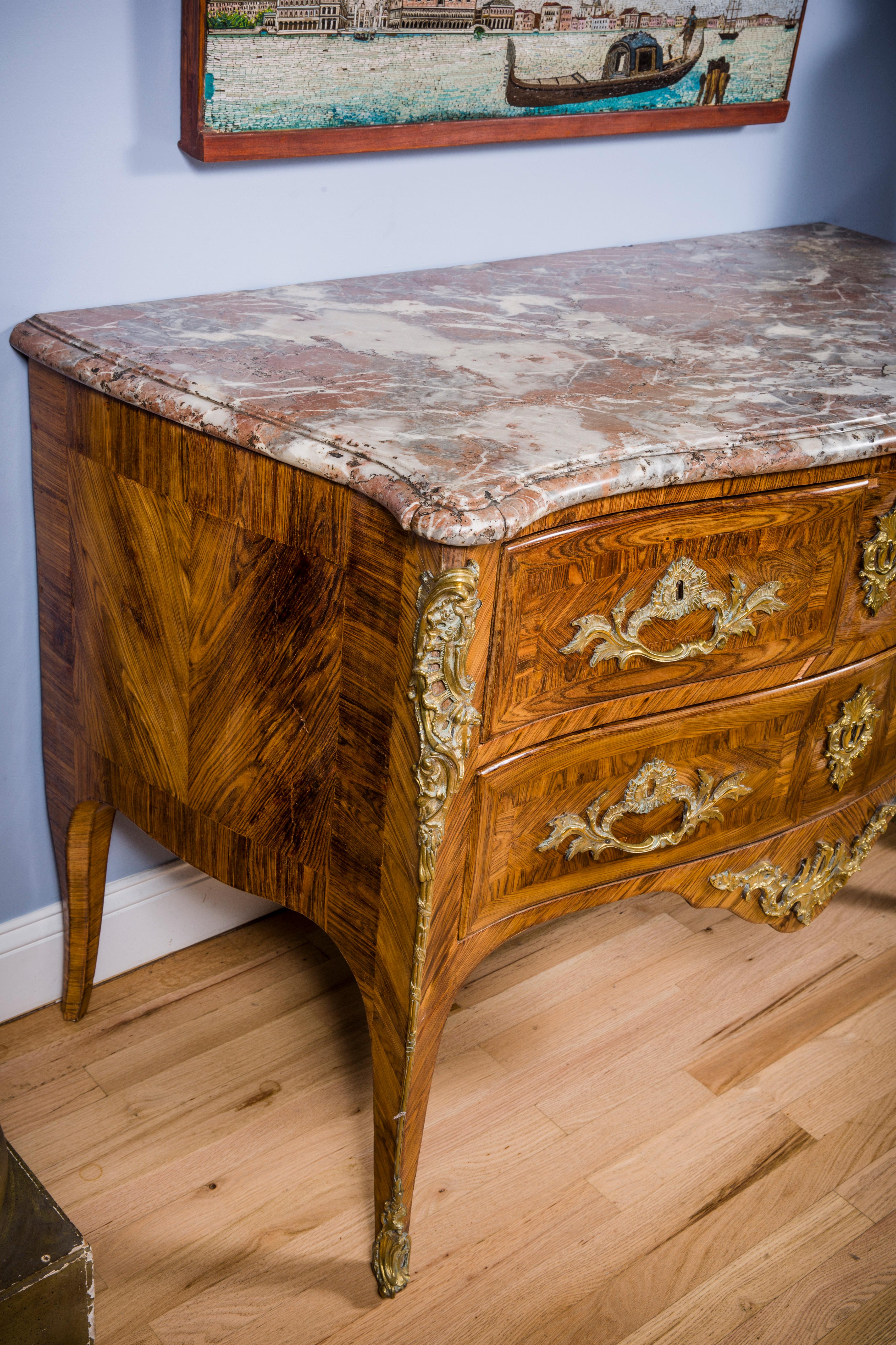 Louis XV Ormolu-Mounted Kingwood Commode
by Nicolas Jean Marchand, c. 1735.
The serpentine form commode has two small drawers above a single long drawer. The commode is mounted with ormolu handles, key escutcheons, chutes, and an apron mount.