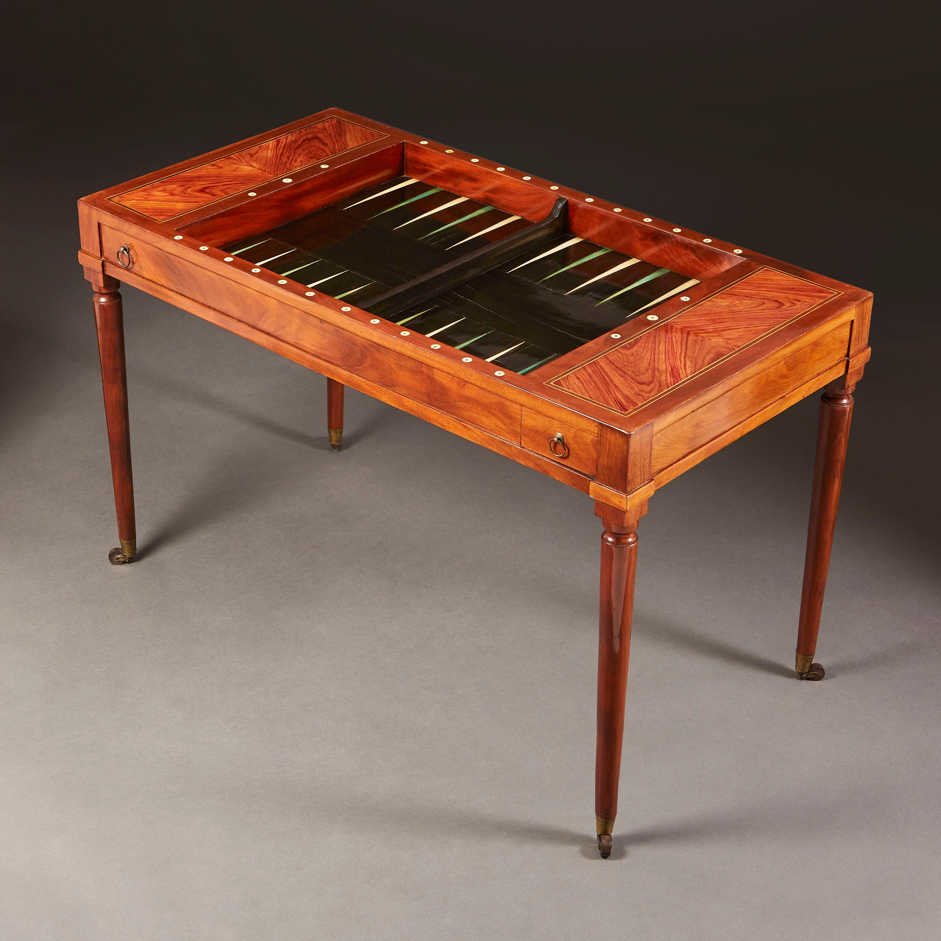 An early nineteenth century kingwood backgammon table with detachable top and ebonised playing surface, stained triangular lozenges, all supported on cylindrical legs, terminating in topie castors.
