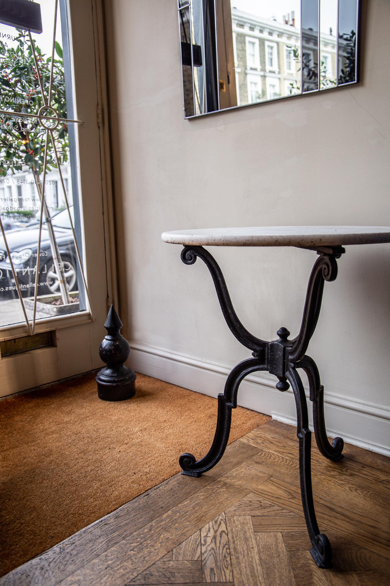 With stunning sculptural form - heavy ebonized wrought iron and beautifully patinated original Carrara marble top. An ideal early example, featuring scrolls to top and feet of base and central finials.
 
