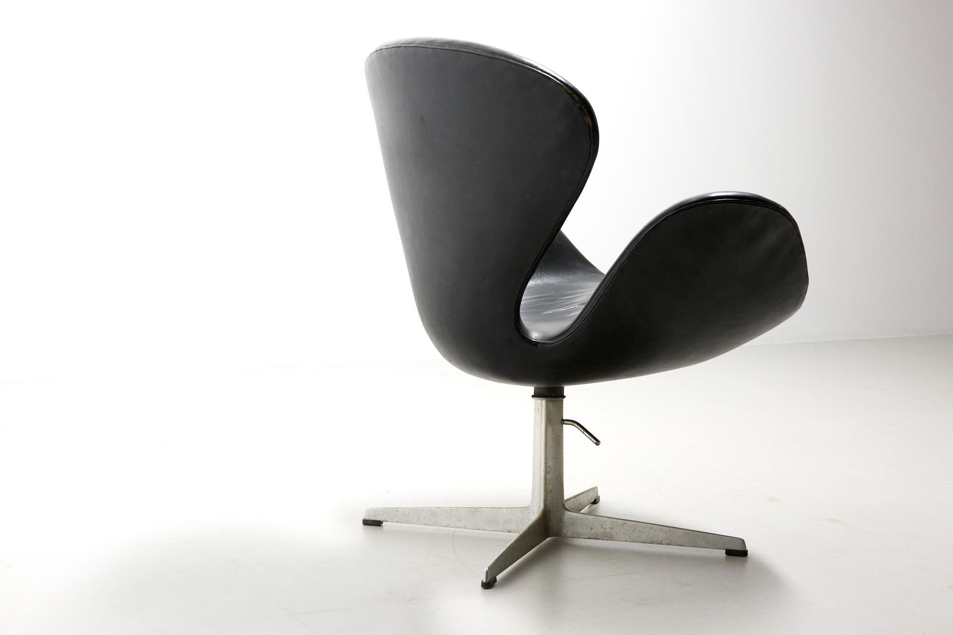A swan lounge chair with swivel base, adjustable in height. Original black leather in good condition. Design by Arne Jacobsen in 1958 for the SAS Royal Hotel in Copenhagen. The shape of the star foot and construction of the shell indicate that this