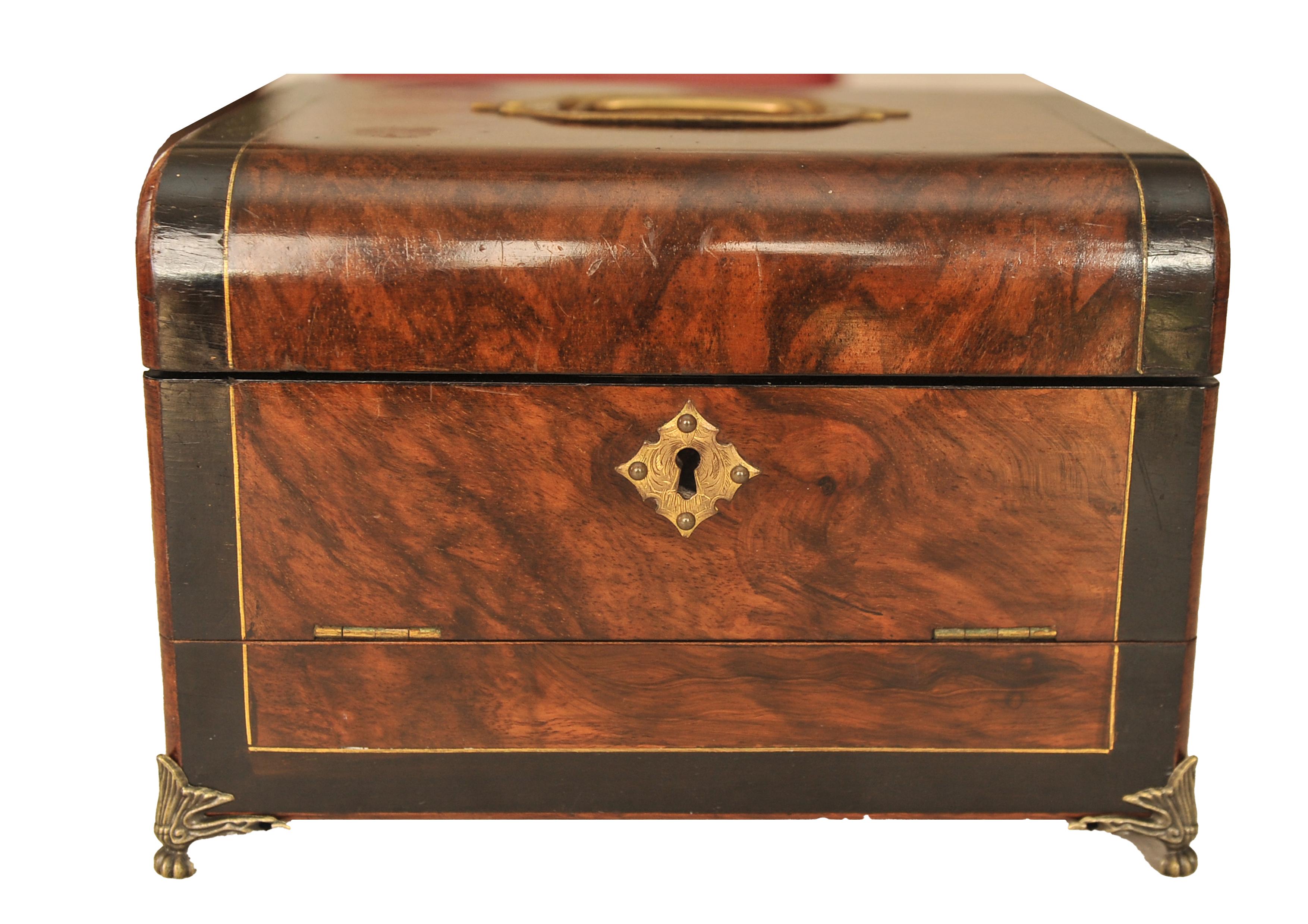 An Early Victorian Burr Walnut Velvet Cushion Lined Ladies Dressing Box 

Box features an elegant ebonised banding.
The domed cover with central brass carrying and fall front handle opening to reveal a fitted interior with lift out tray and three